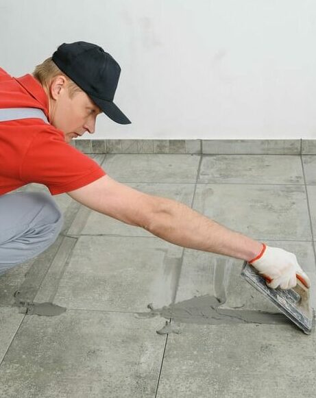 Grouting ceramic tiles. Tilers filling the space between tiles using a rubber trowel.