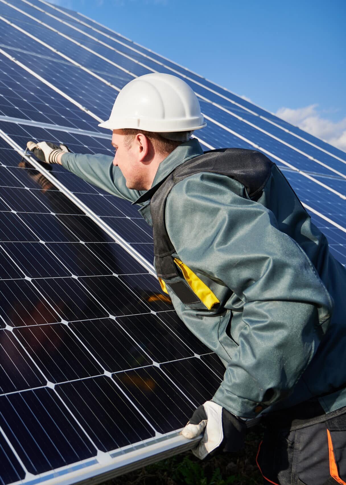 Man technician in safety helmet repairing photovoltaic solar module. Electrician in gloves maintaining solar photovoltaic panel system. Concept of alternative energy and power sustainable resources.