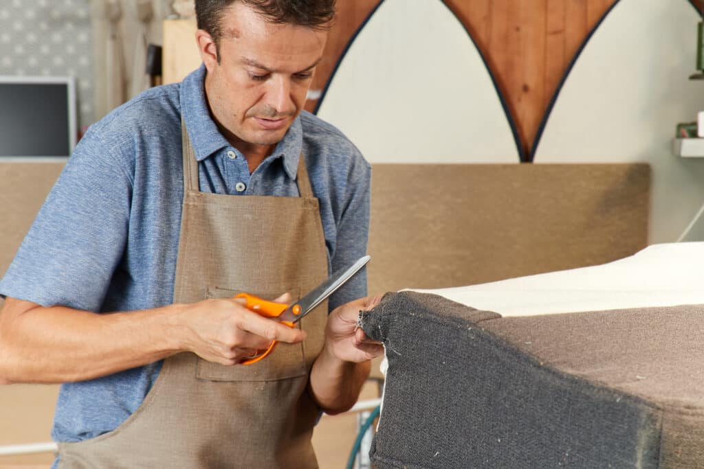 Qualified workman upholstering furniture in repair furniture workshop