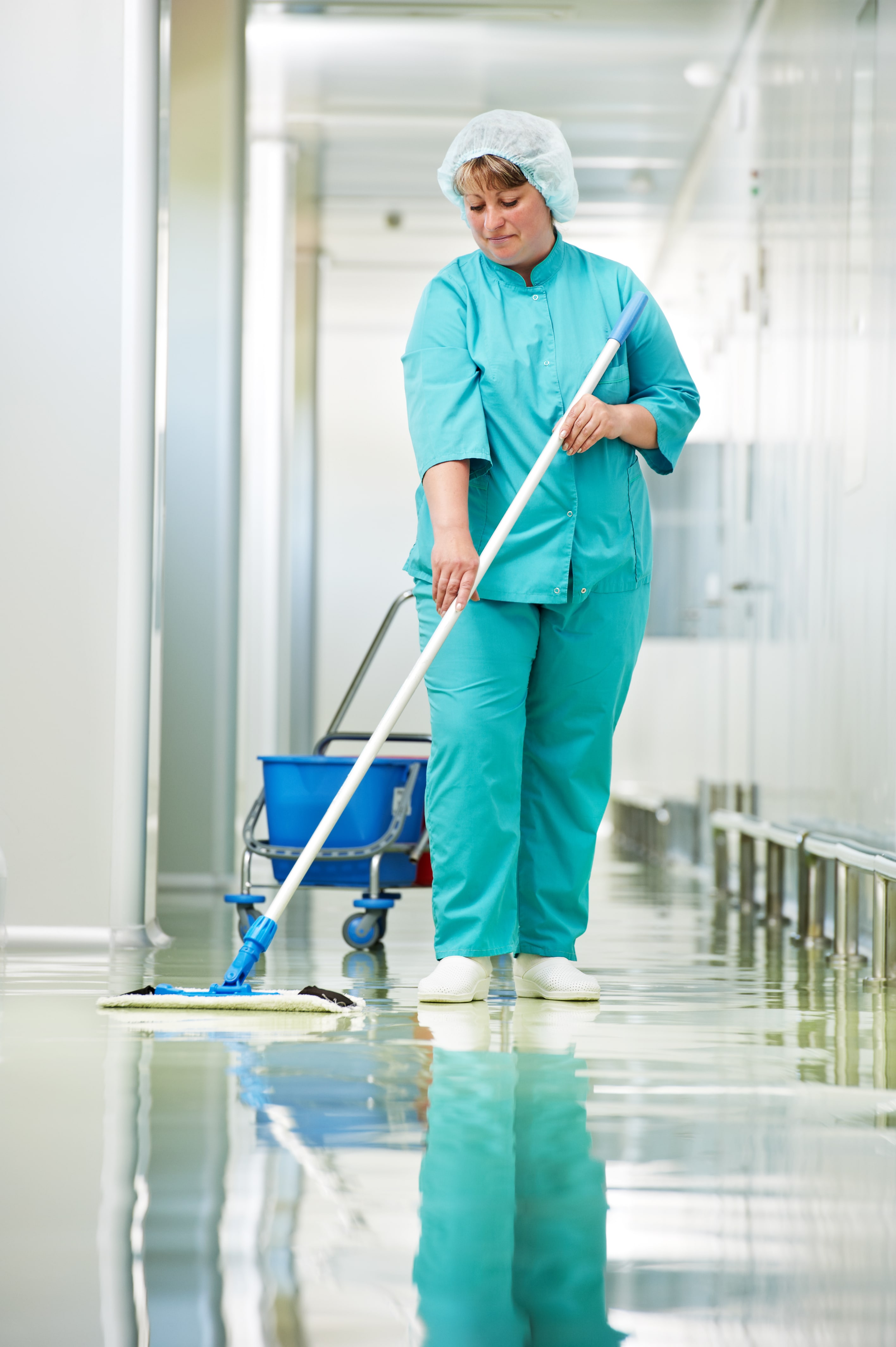 Adult Industrial Cleaner woman with mop and uniform cleaning corridor pass floor of pharmacy industry factory or clinic