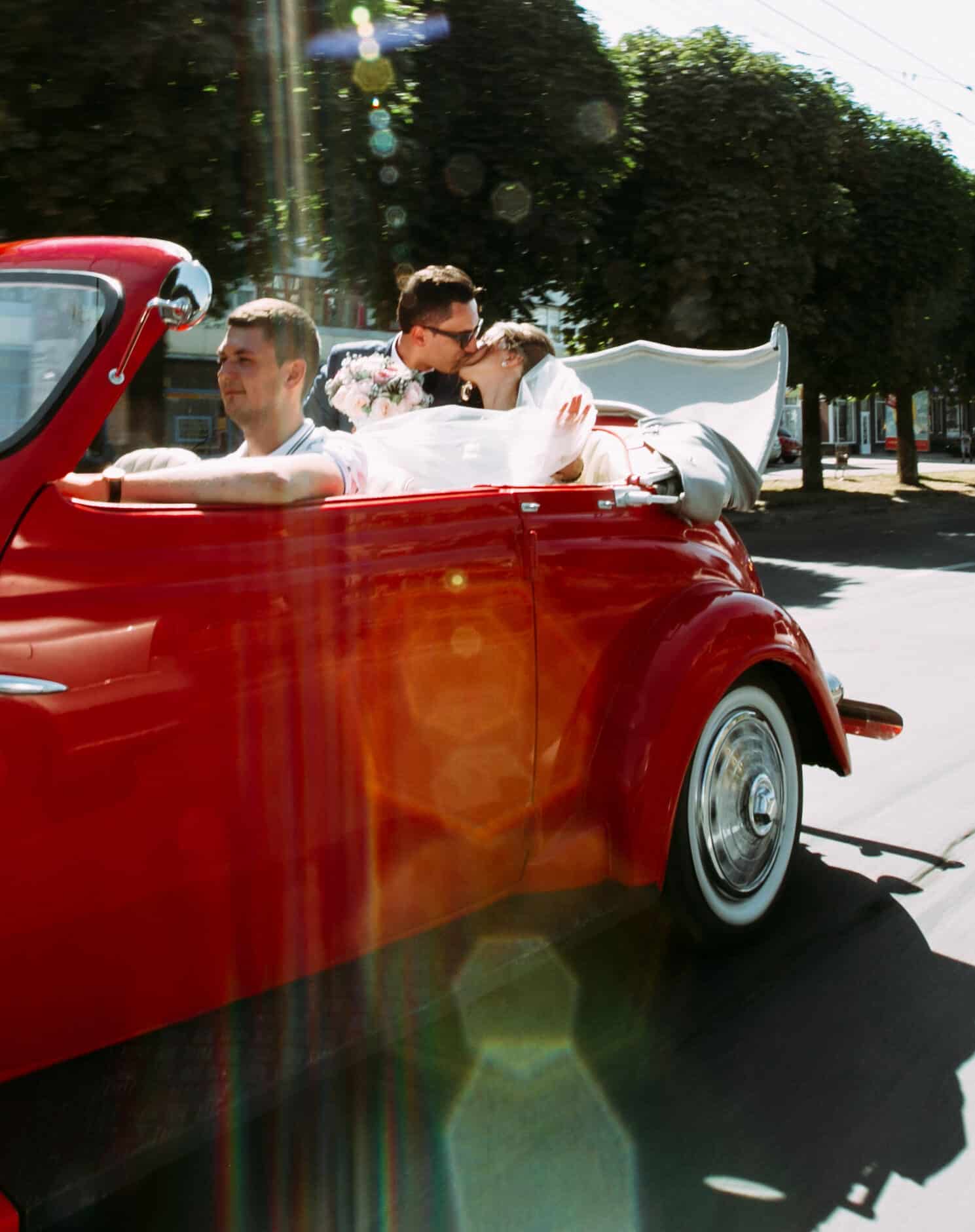 Kiss of the just married couple in the old wedding car