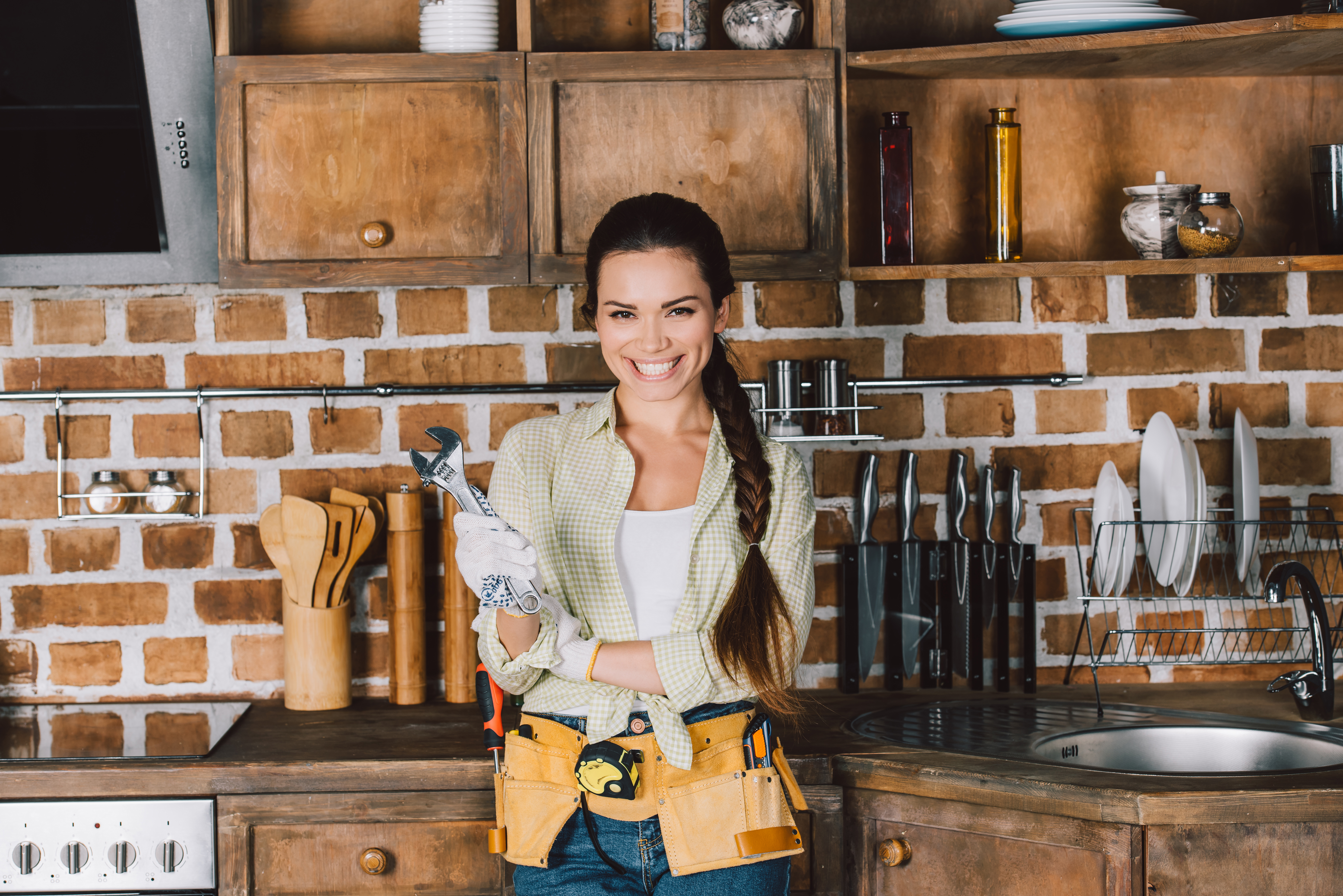 Happy young repairwoman with wrench standing at Timber Bespoke Kitchen