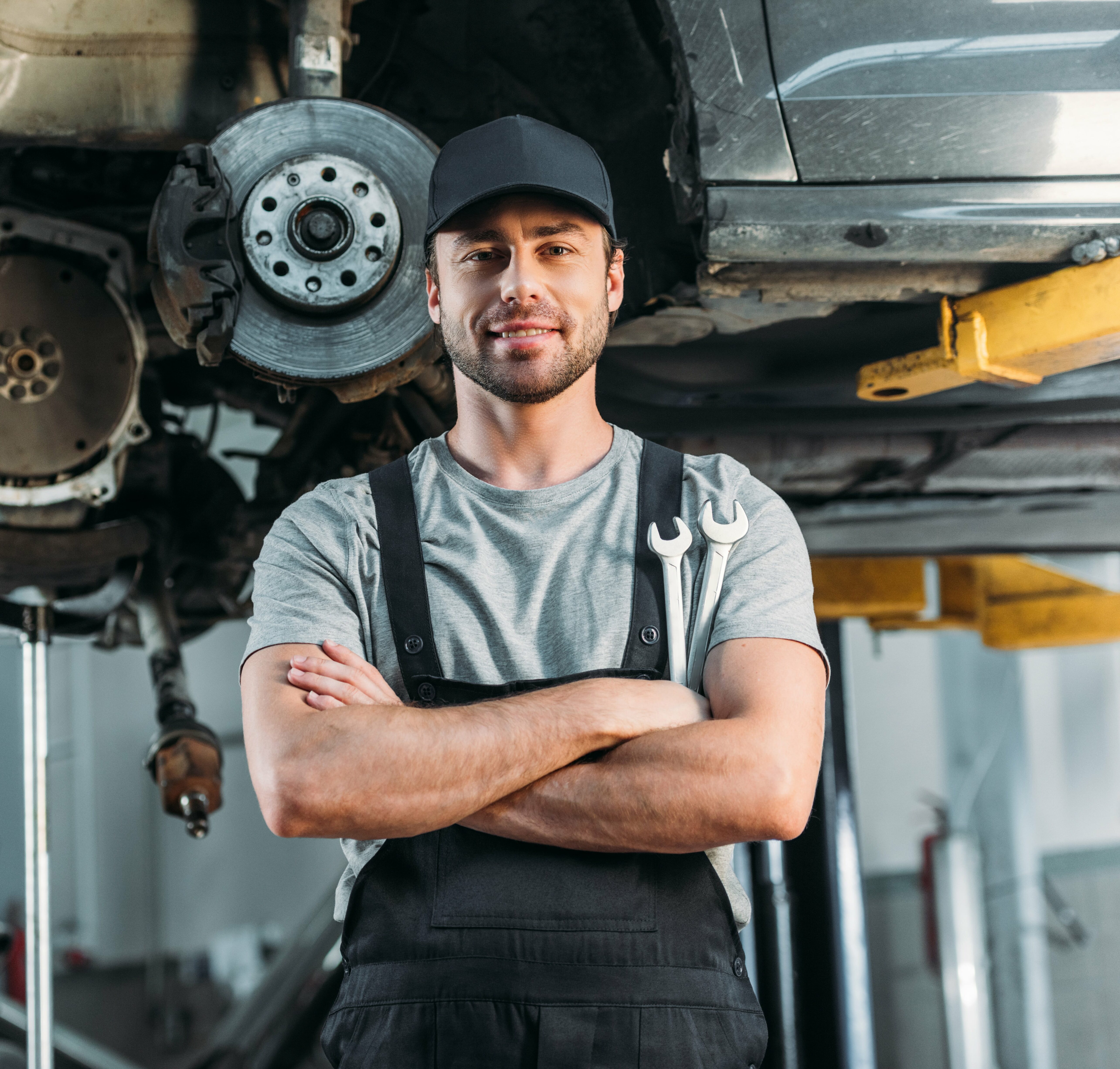 Portrait of mechanic in front of car being repaired