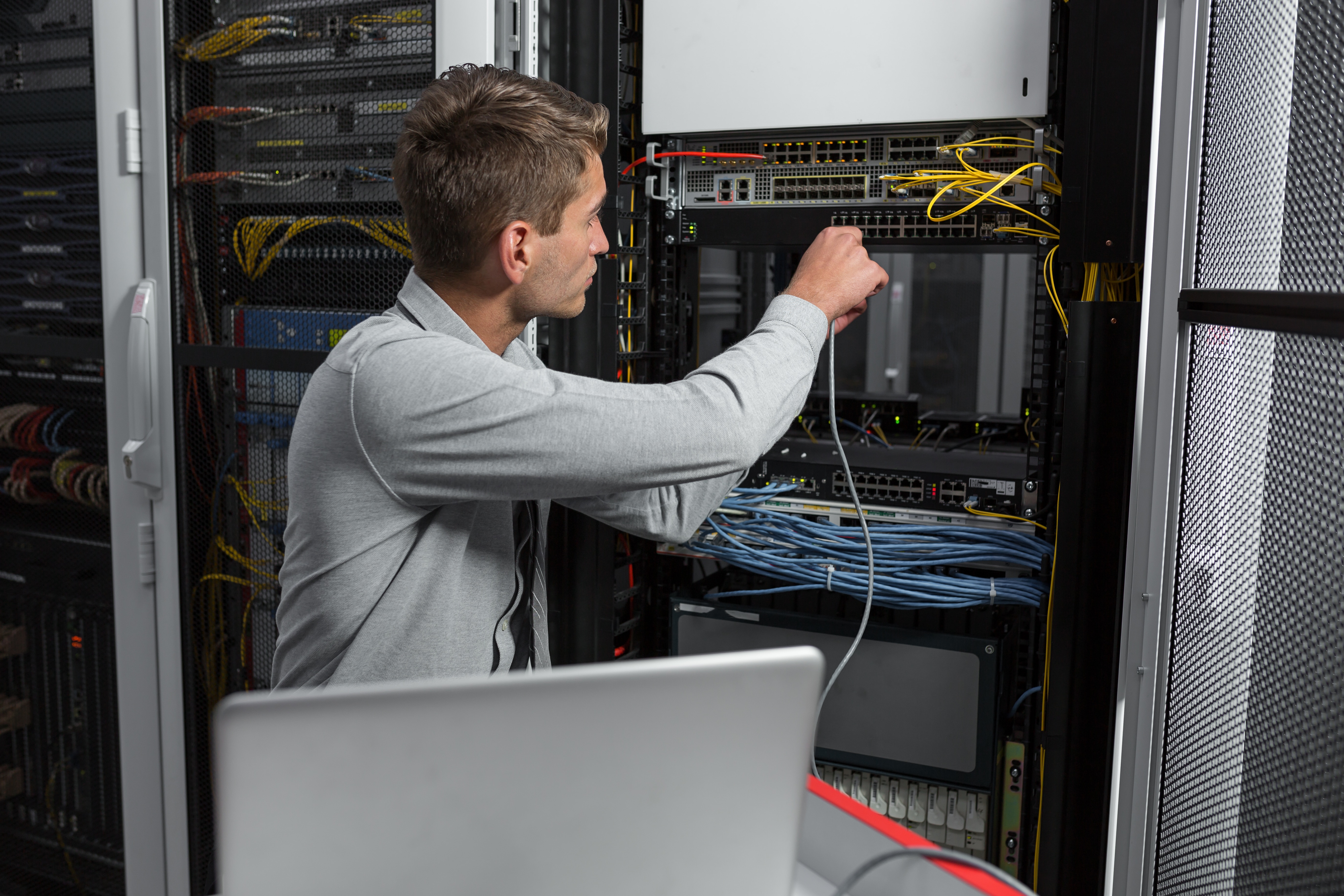 Portrait of a young man engeneer in datacenter server room, ddoing some Data Cabling service