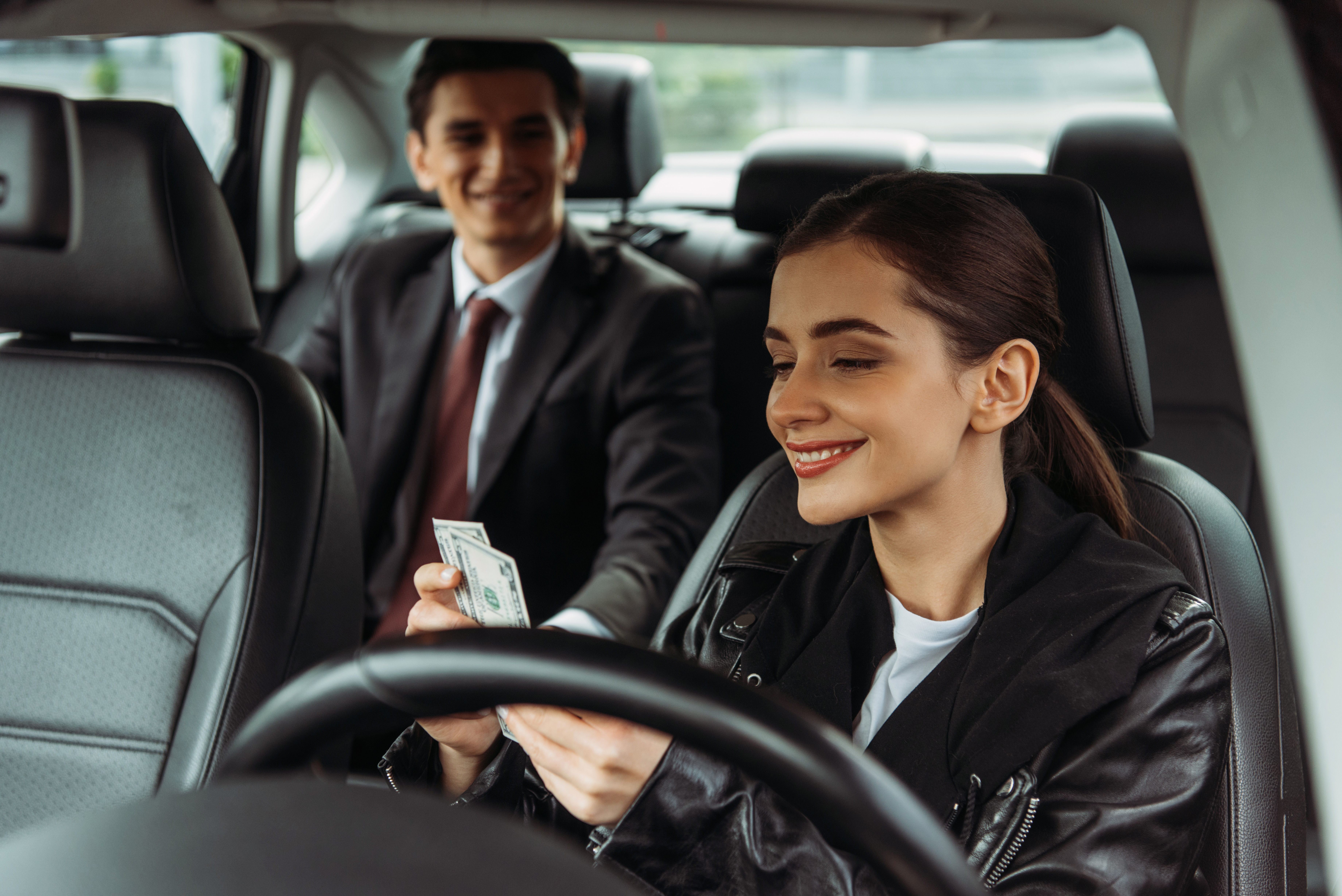 Portrait of a Airport Transfers woman driving a man and receving money after the drive