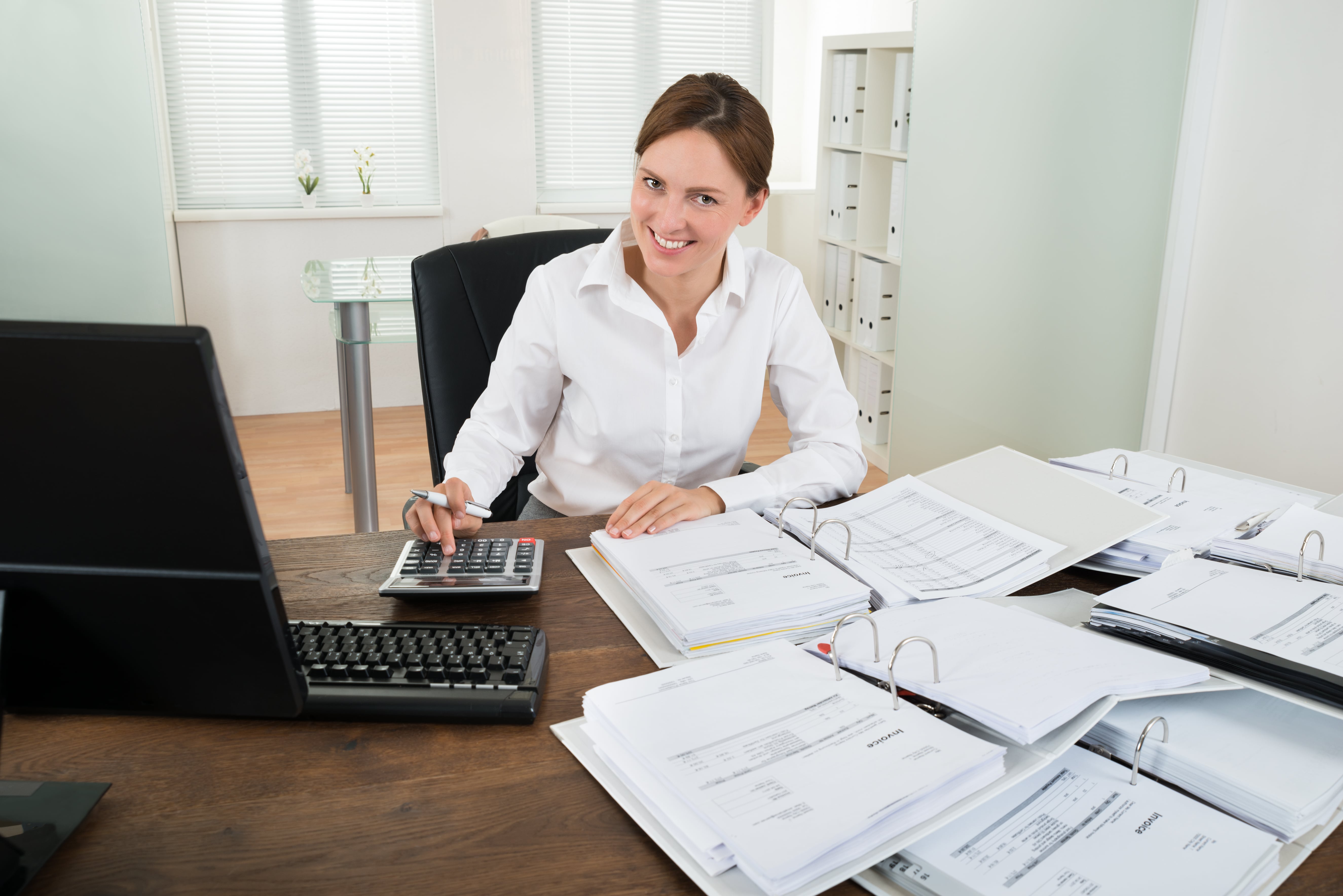 Happy Businesswoman Calculating Financial Data With Calculator At Desk, Bookkeeper