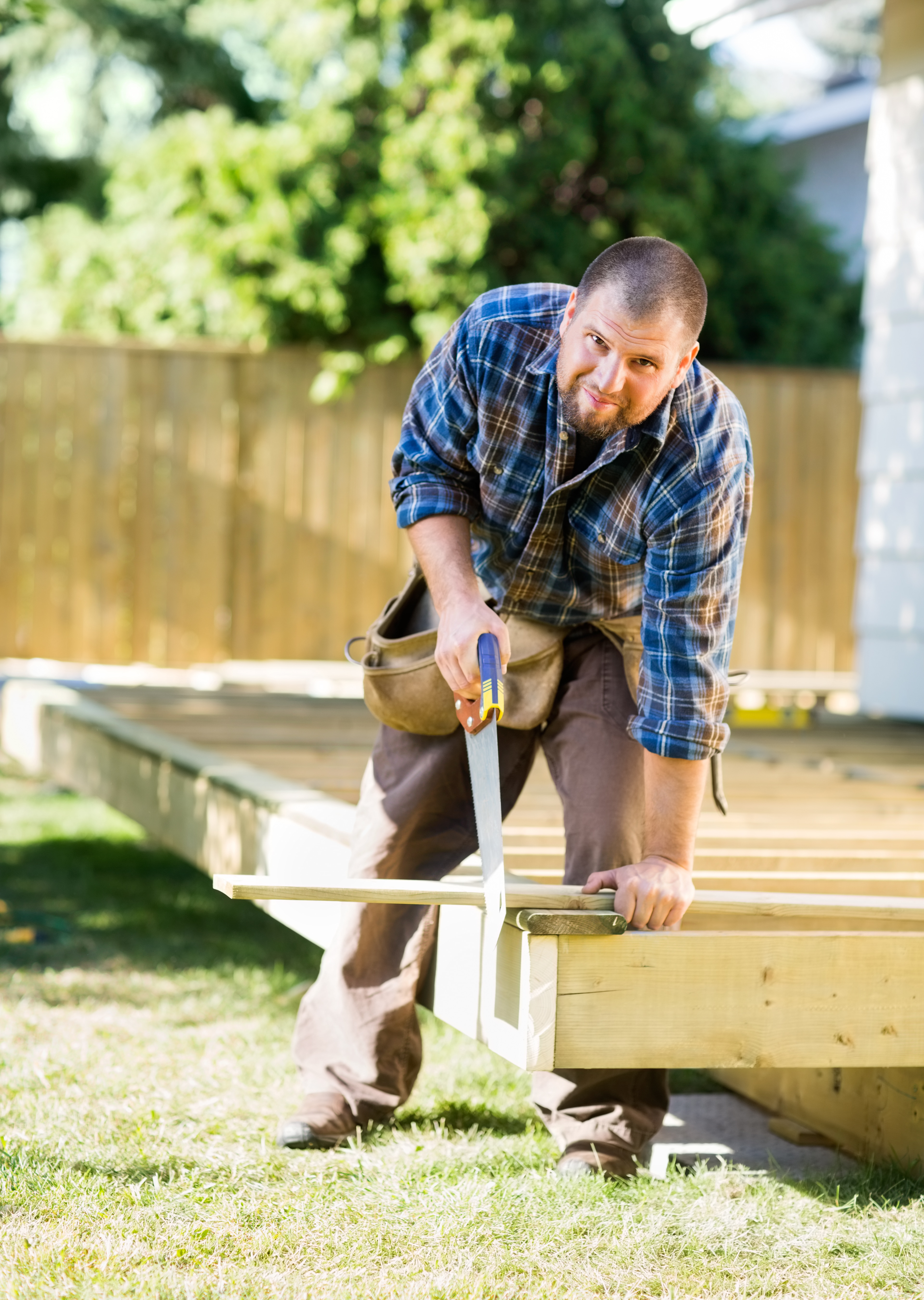 Full length portrait of confident mid adult worker cutting wood making a Garden Decking