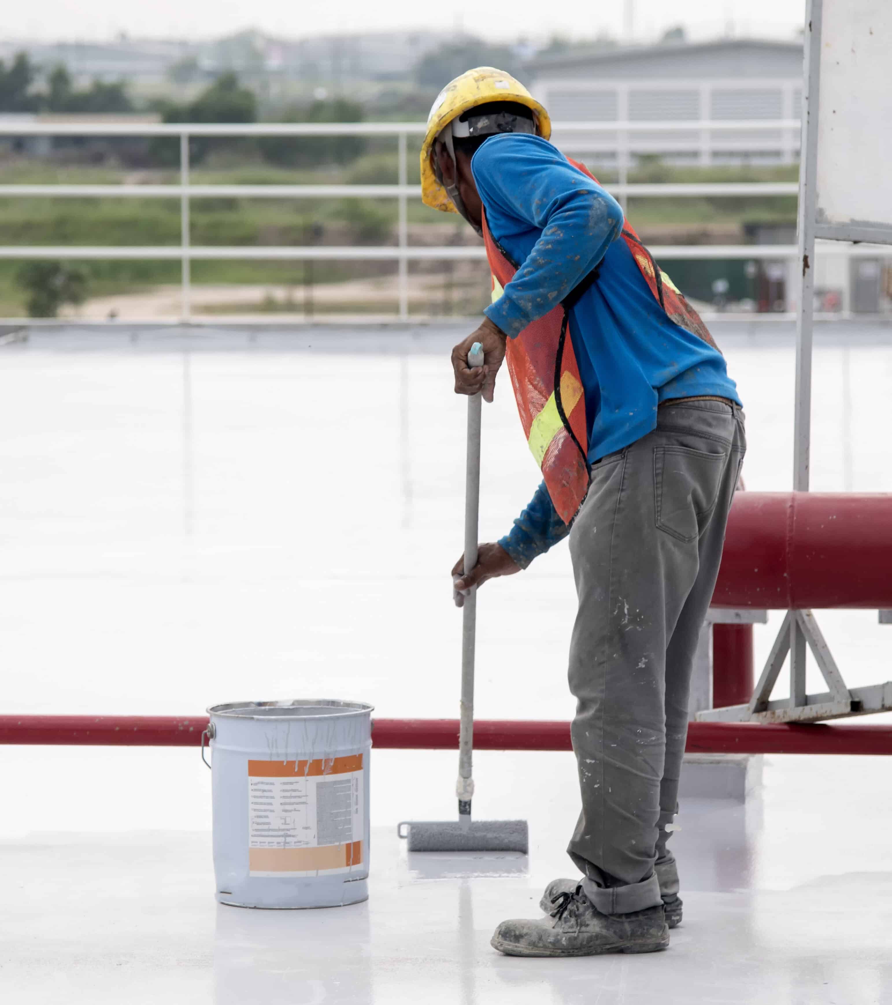 Construction worker coating epoxy paint at roof slab for water proof protection