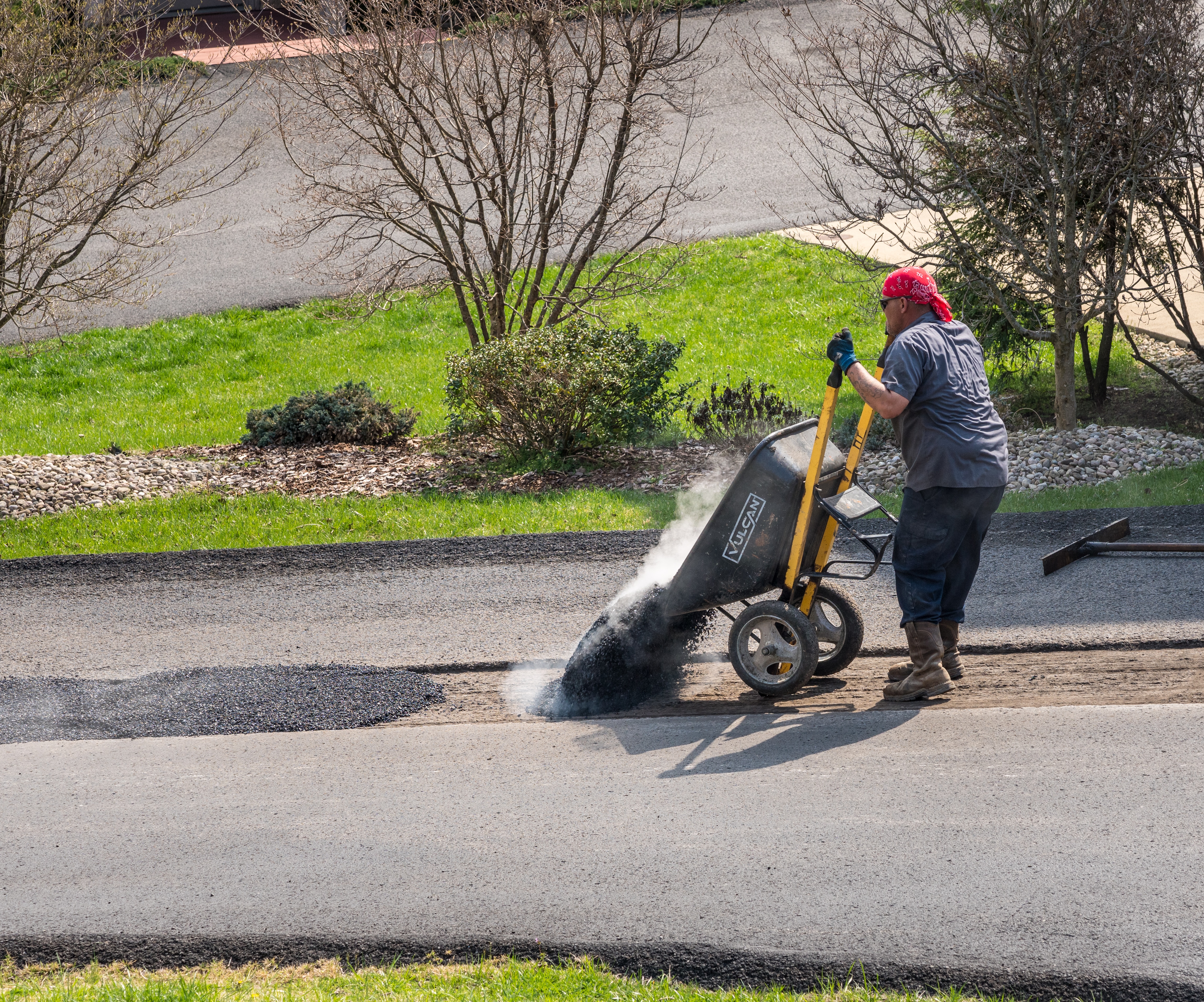 Workers applying extra blacktop to do Driveway Repairs asphalt street