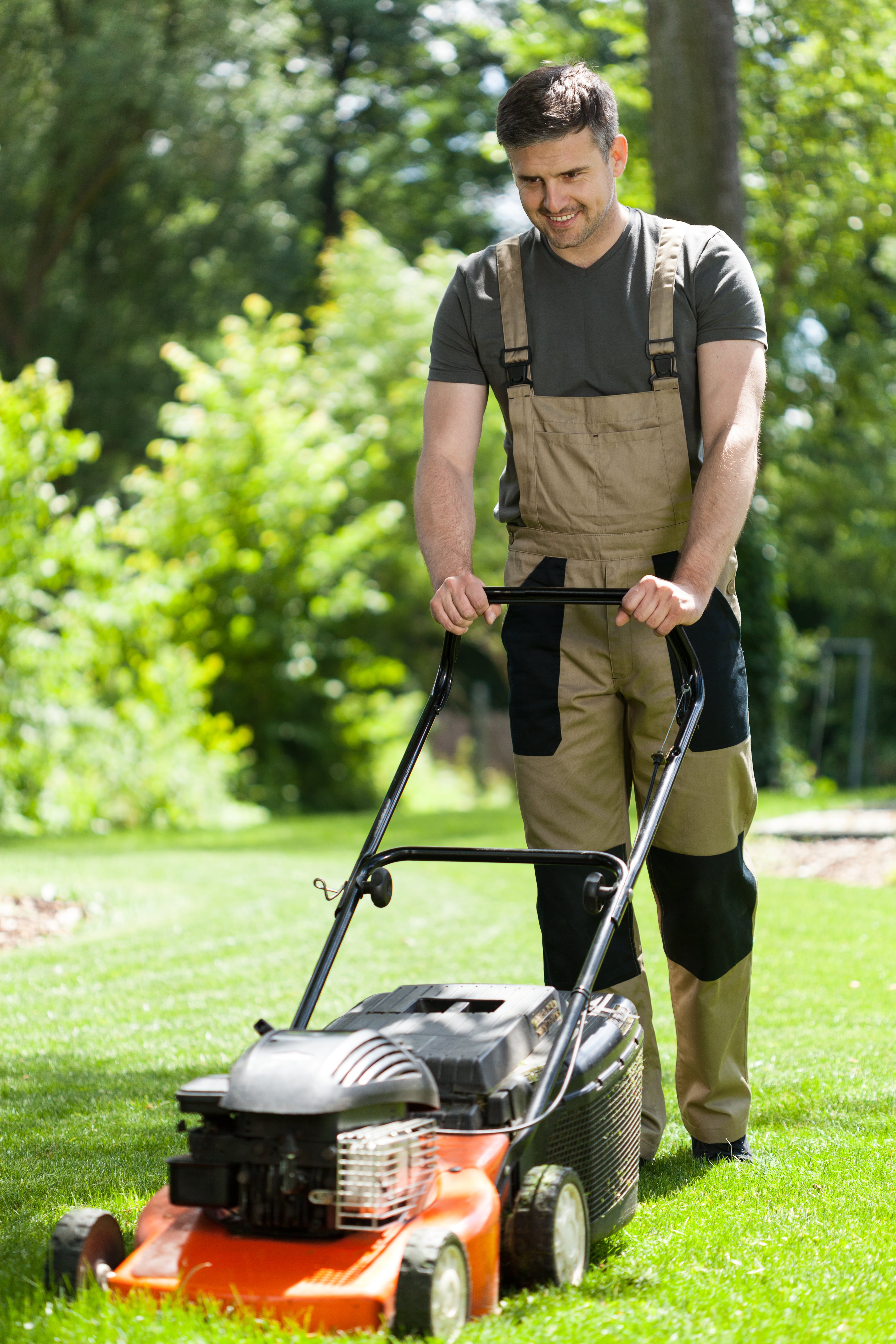 Man in work overalls Grass Cutting, vertical