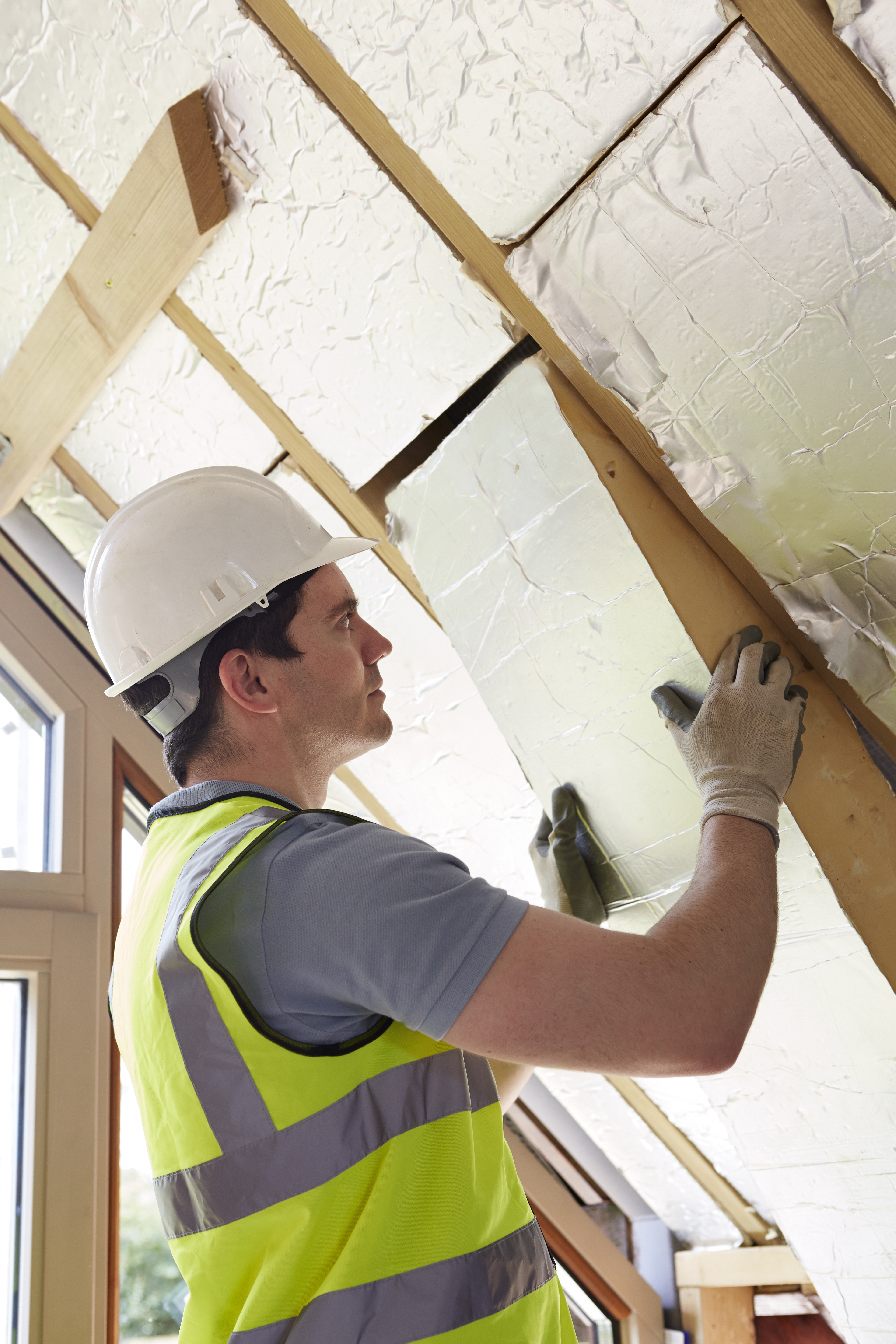 Builder Fitting Insulation Boards Into Roof Of New Home