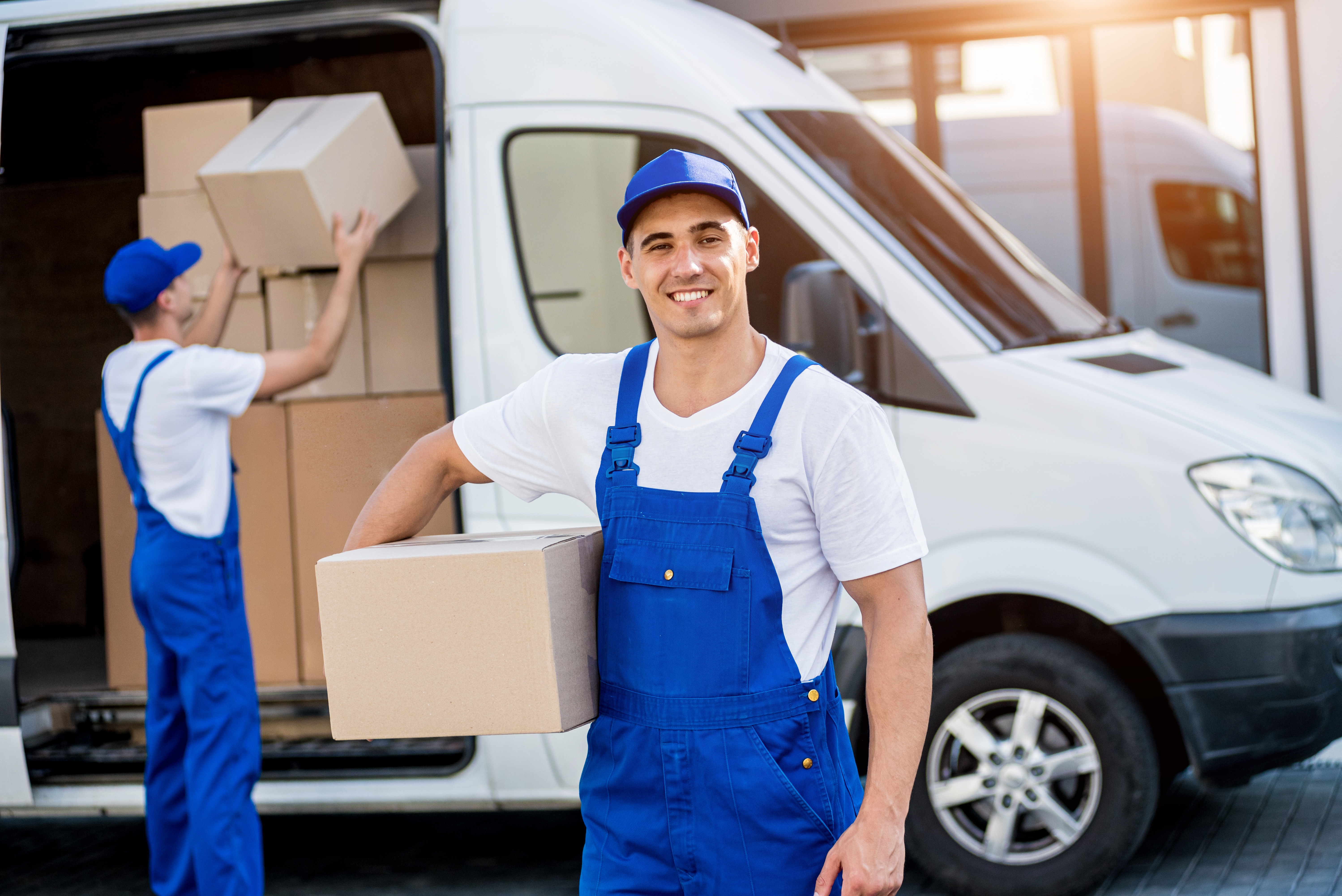 Portrait of a Courier Services Man unloading boxes from minibus into new home.