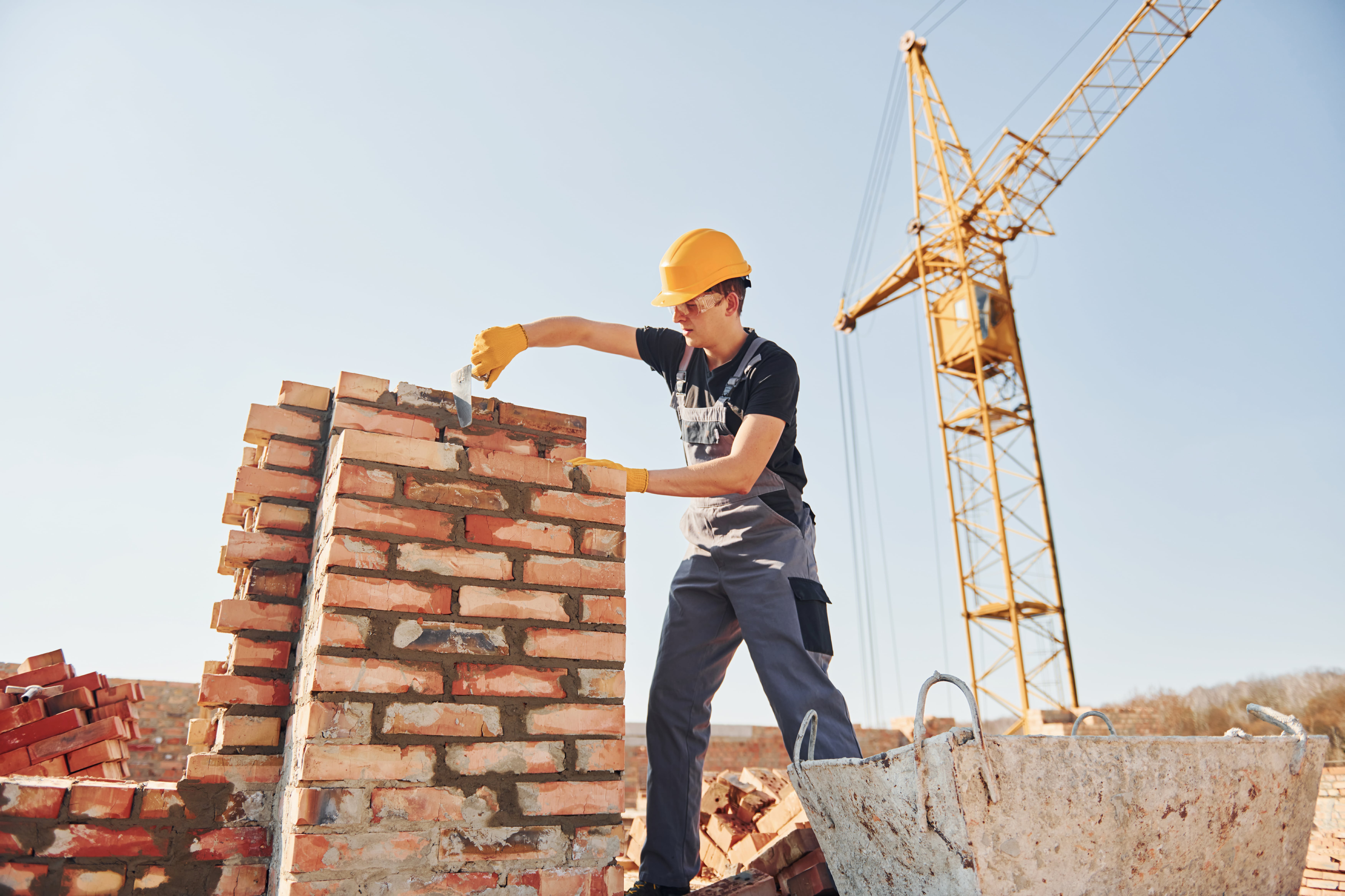 Installing brick wall. Construction worker in uniform and safety equipment have job on building.