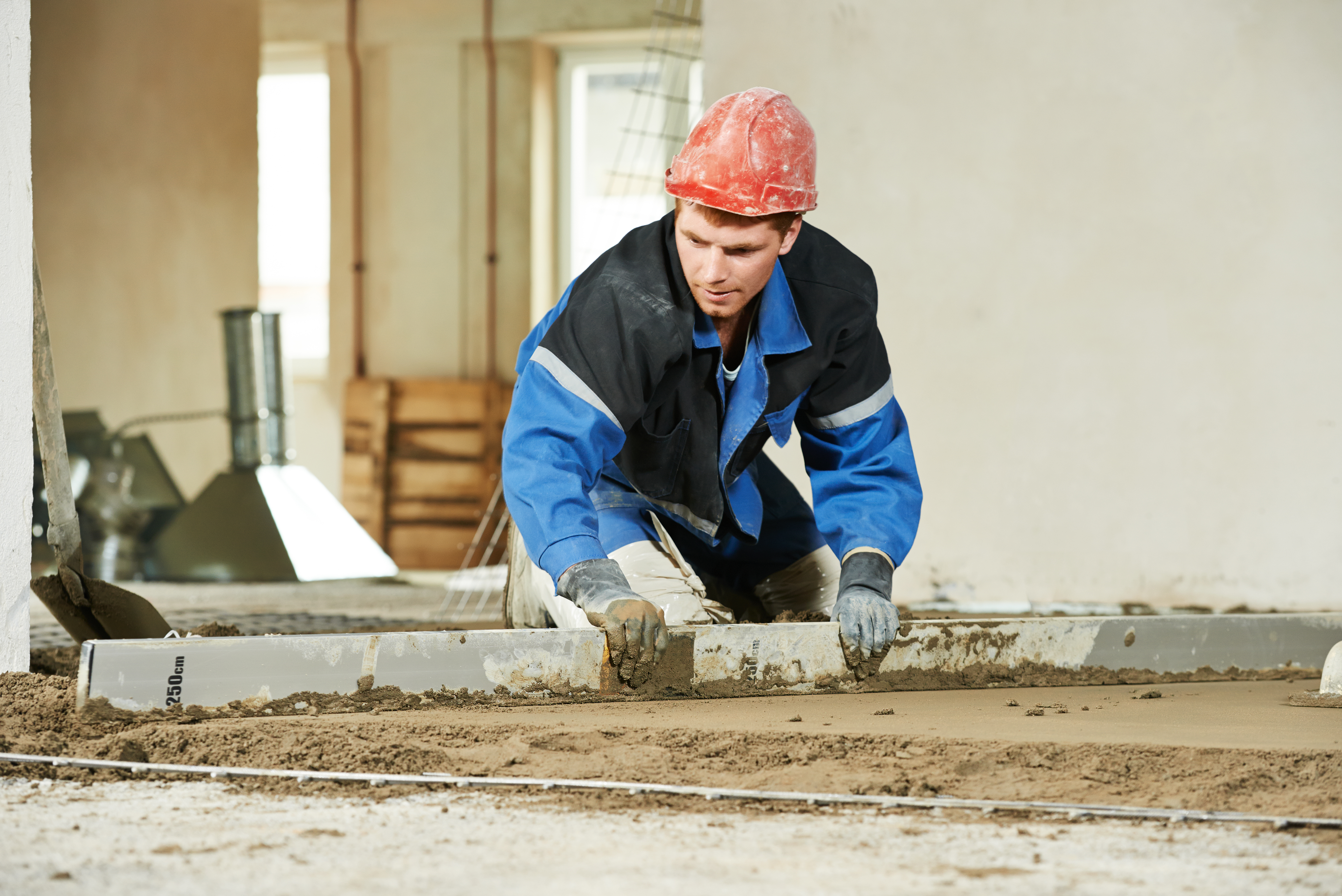 Concrete Resurfacing man indoors working on cement floor topping with float