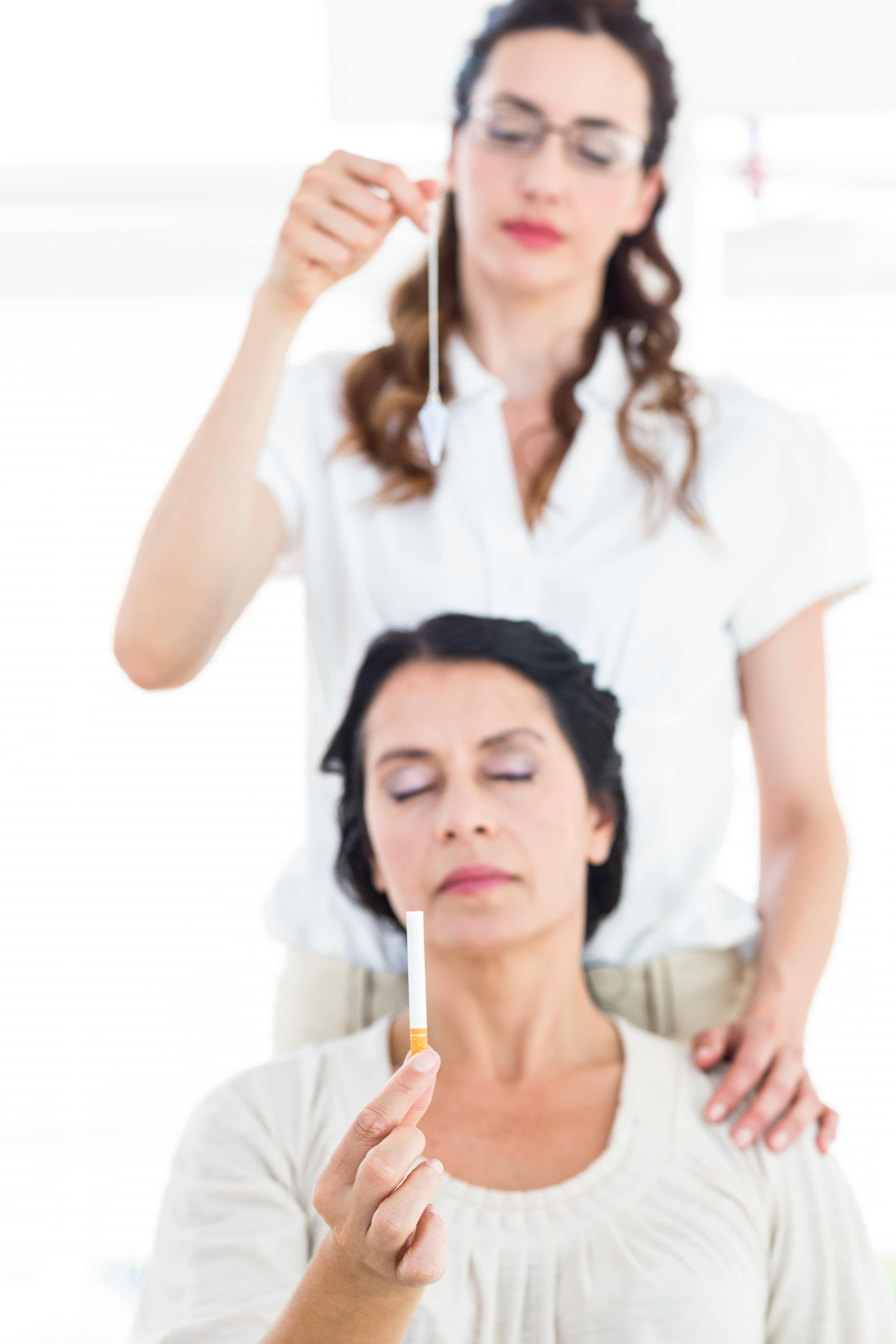 Portrait of a Woman being hypnotized to quit smoking on white background