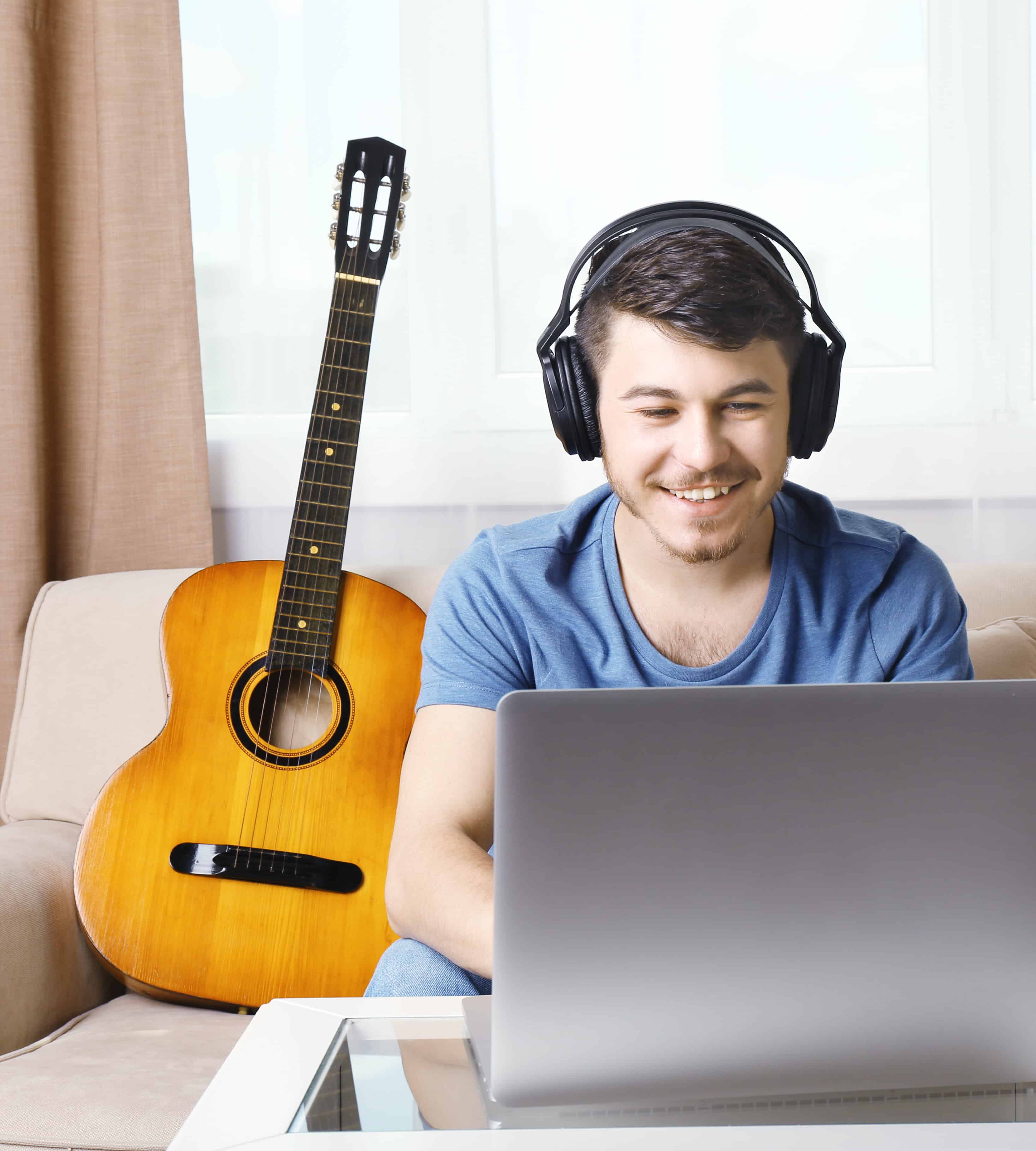 Young man using laptop in room giving an Online Music Lessons