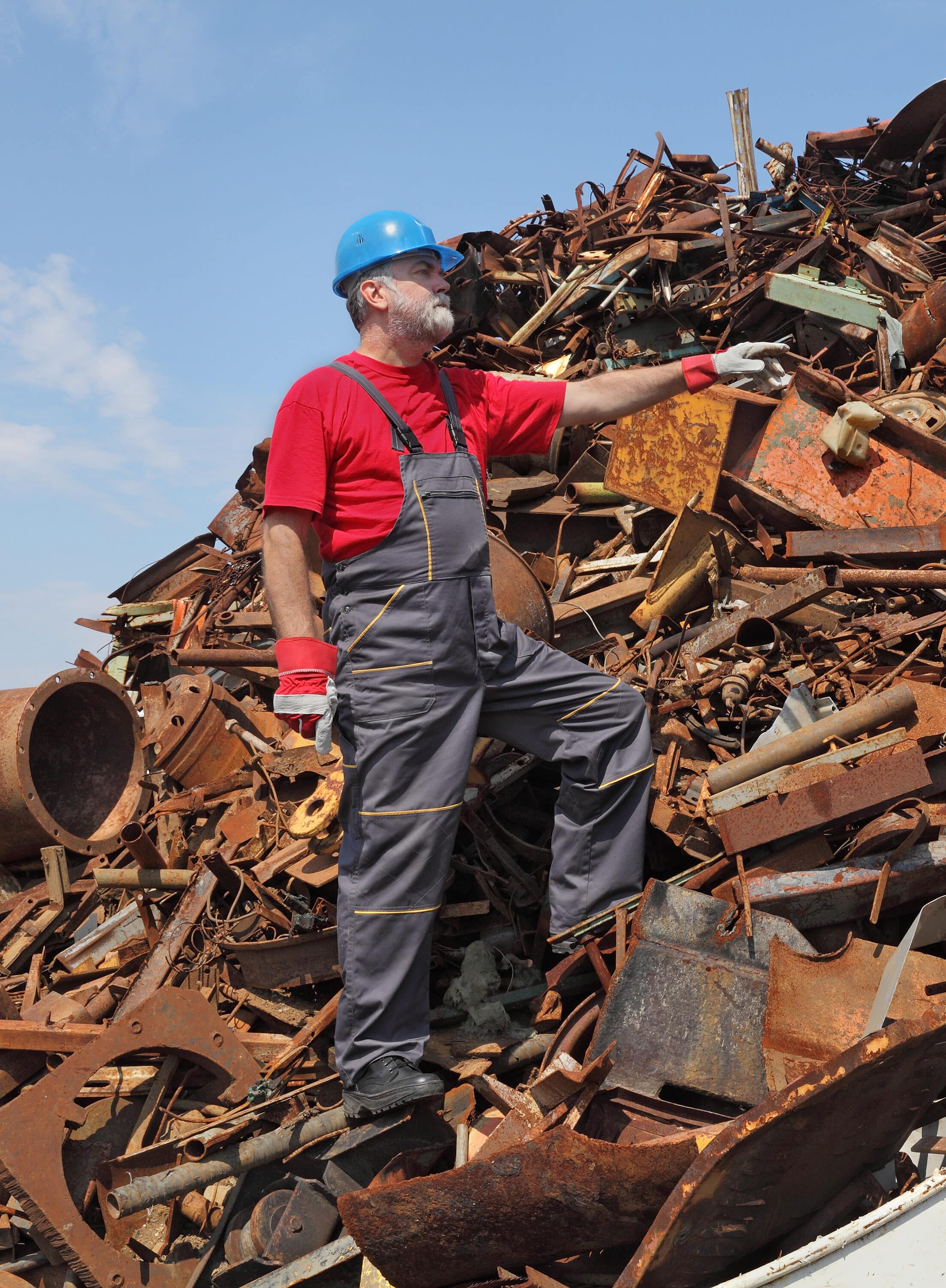 Scrap Metal Clearance Worker gesturing at heap of scrap metal ready for recycling, pointing