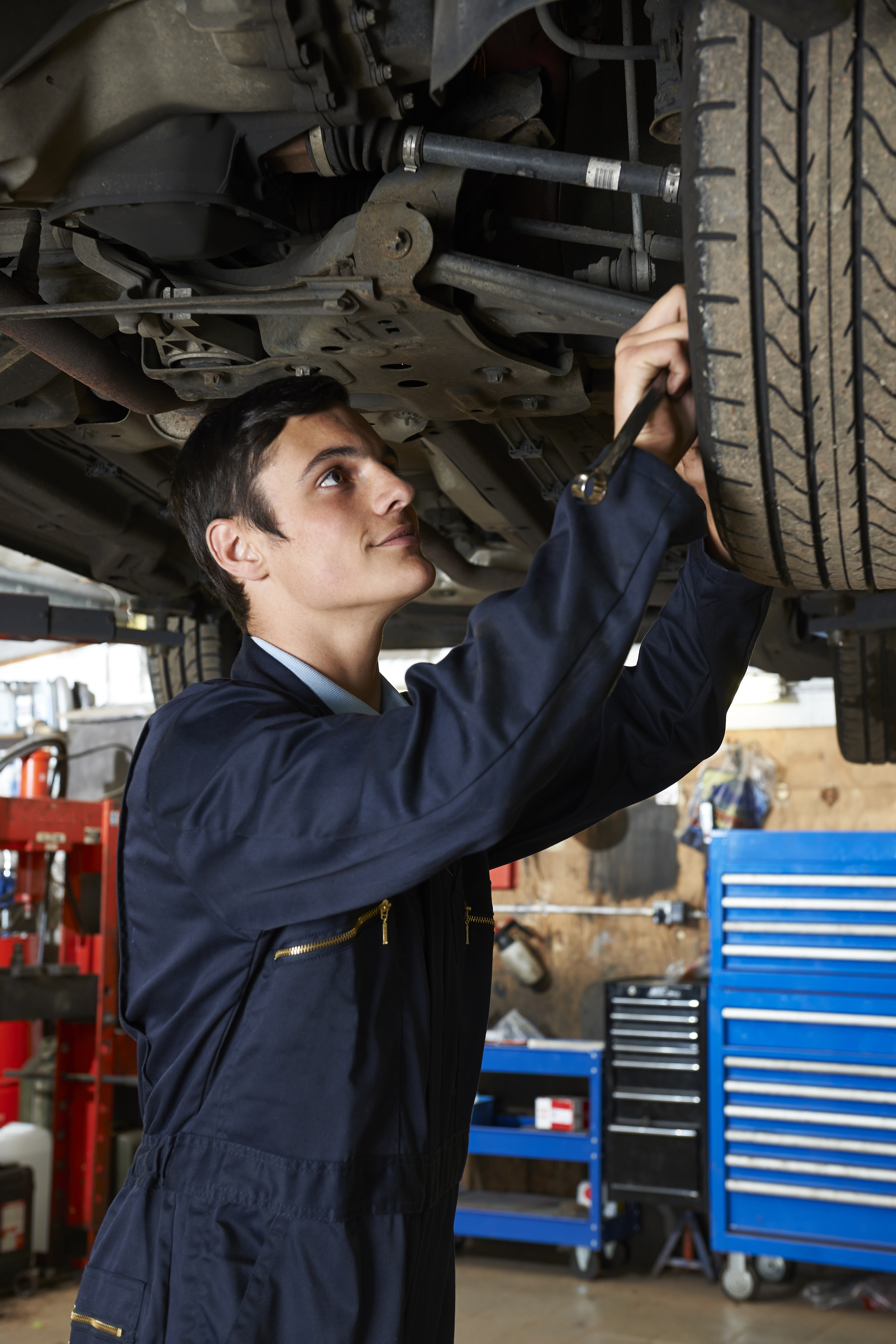 Portrait of a Man doing a Car Suspension service Under Car changing car wheel