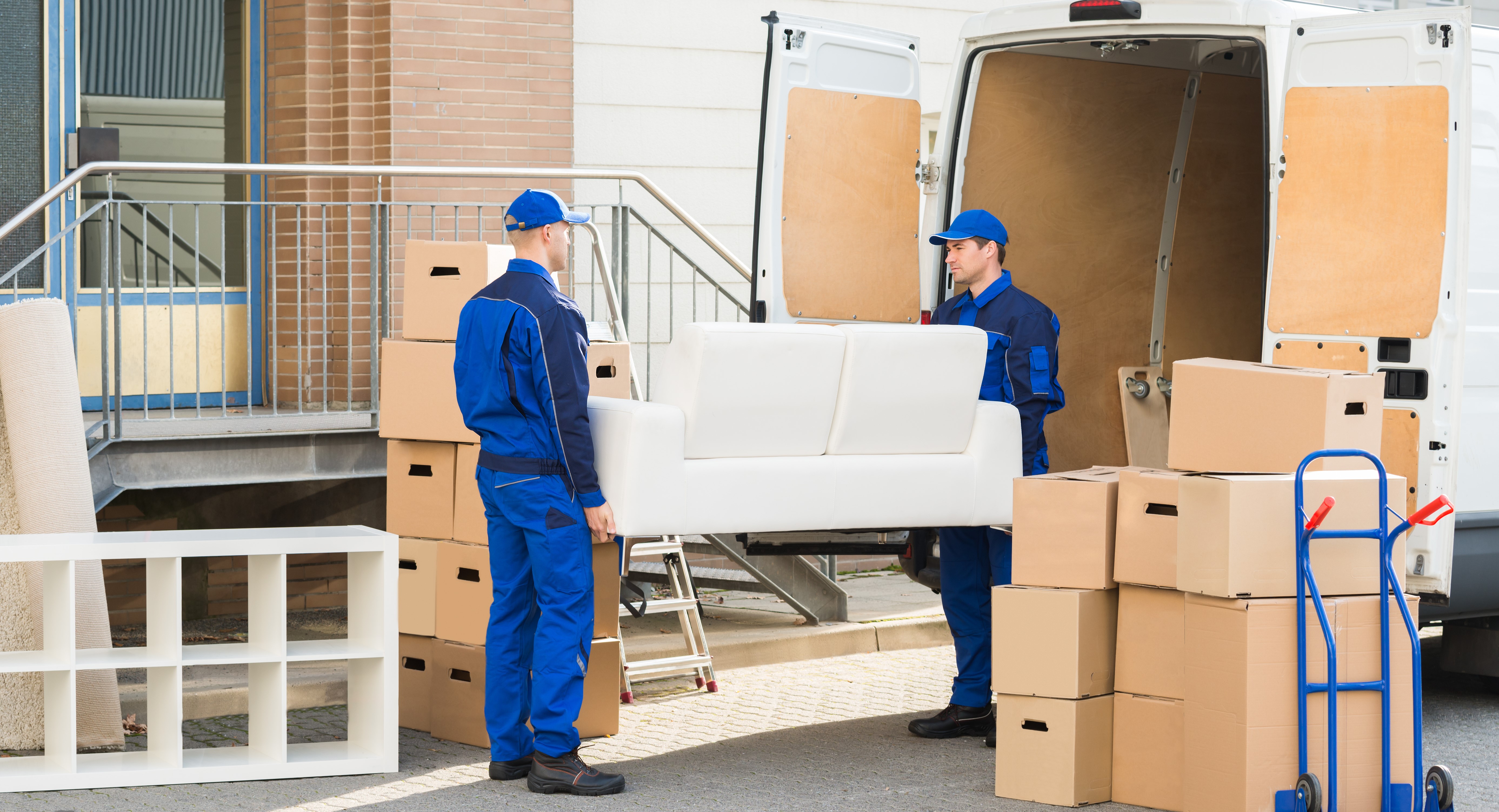 Portrait of a young Packing and Unpacking male movers carrying sofa outside truck on street