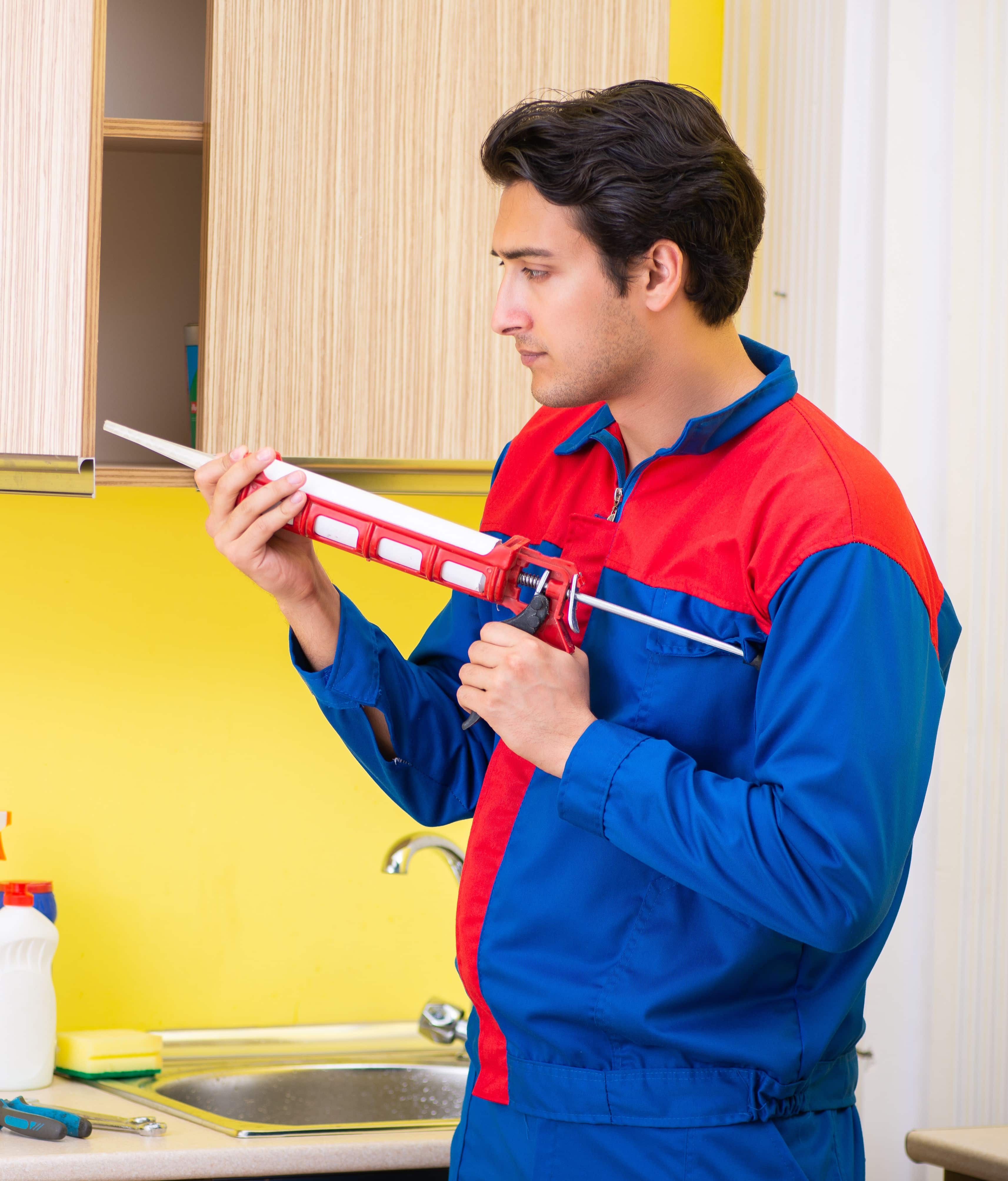 Repairman doing Caulking Services in the kitchen