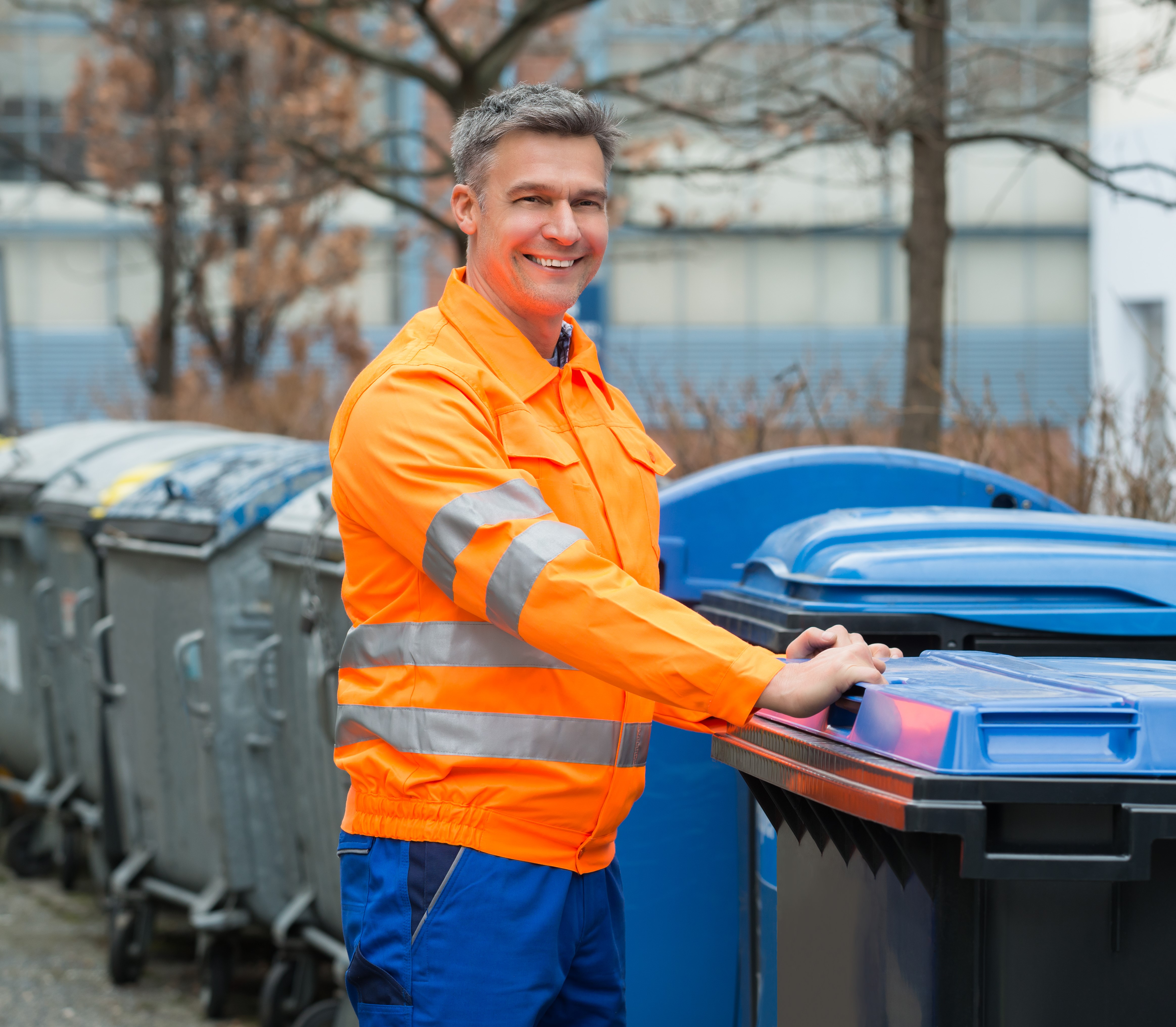 Happy Rubbish Removal Man Standing Near Dustbin On Street