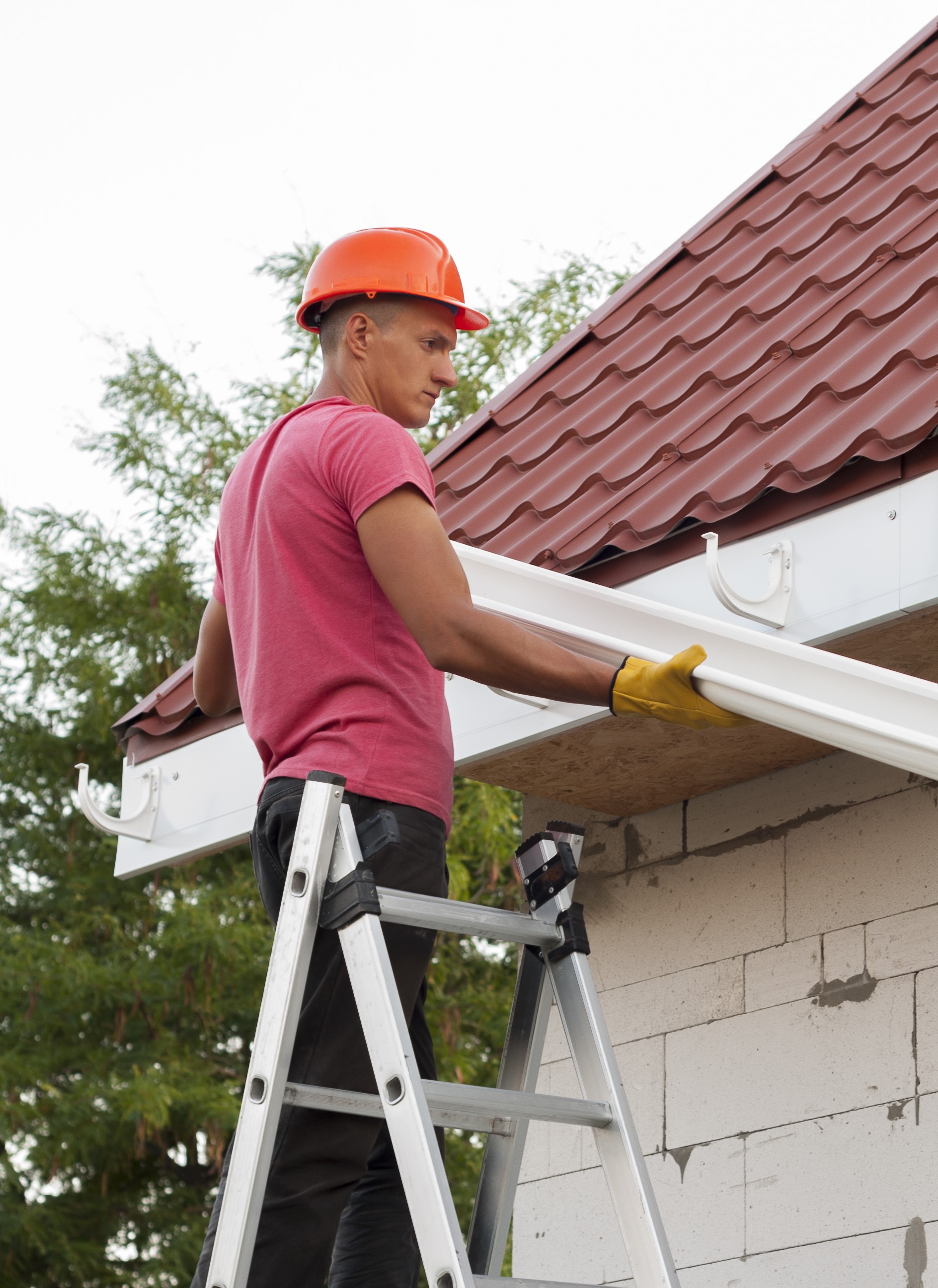 Portrait of a man repairing a gutter while standing on a ladder