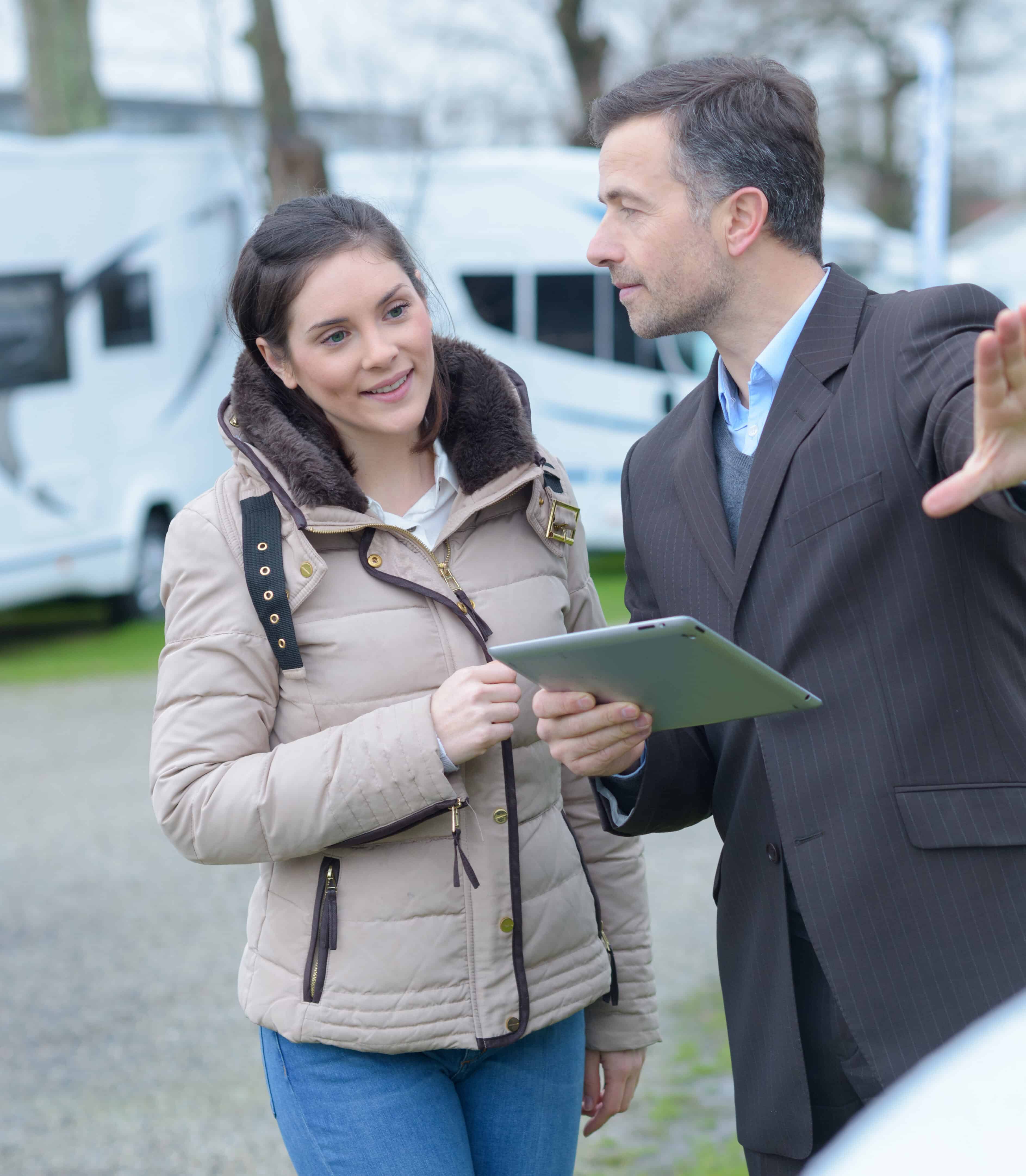 Portrait of a Man giving a Motorhome and Caravan Servicing to a Woman in a parking lot