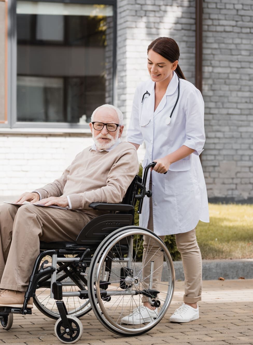 Portrait of a young Woman helping an old Man in a wheelchair