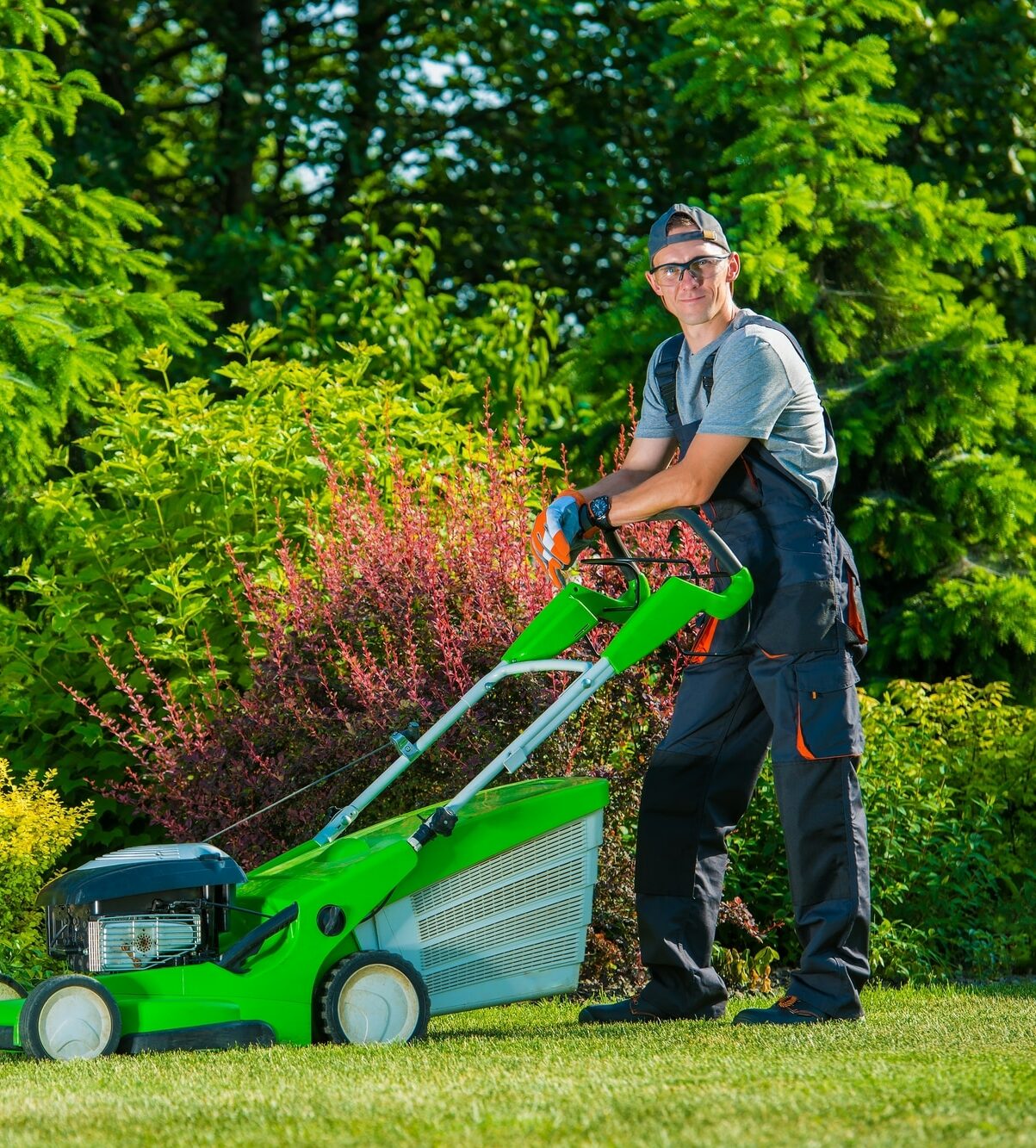 Smiling Professional Gardener with His Gasoline Lawn Mower. Professional Summer Landscaping Works