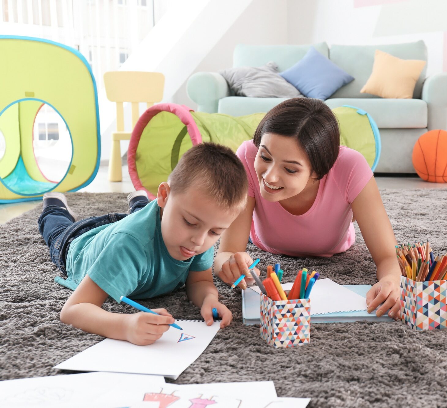 Little boy drawing with nanny at home