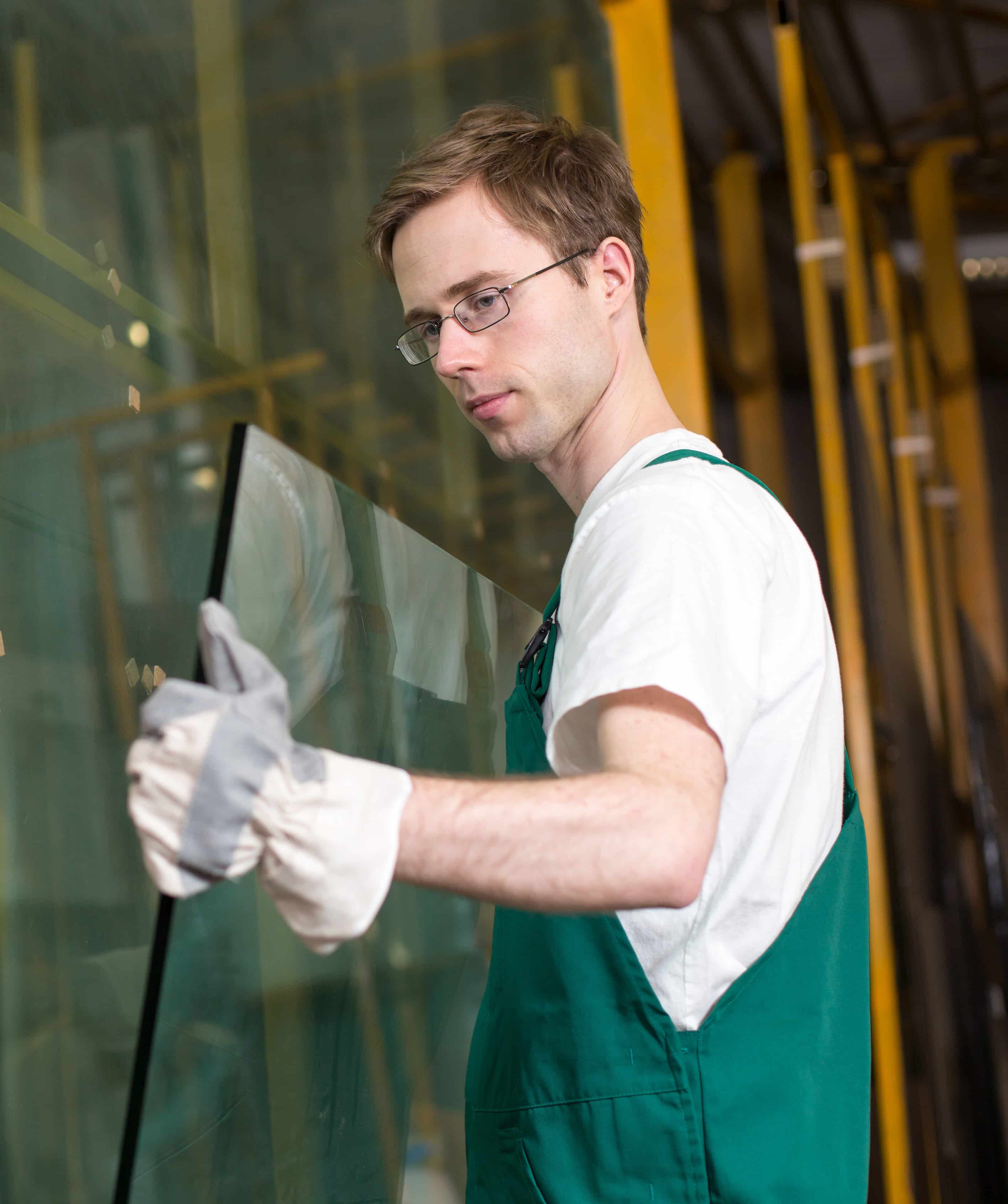 Worker in glazier's workshop, warehouse or storage handling glass