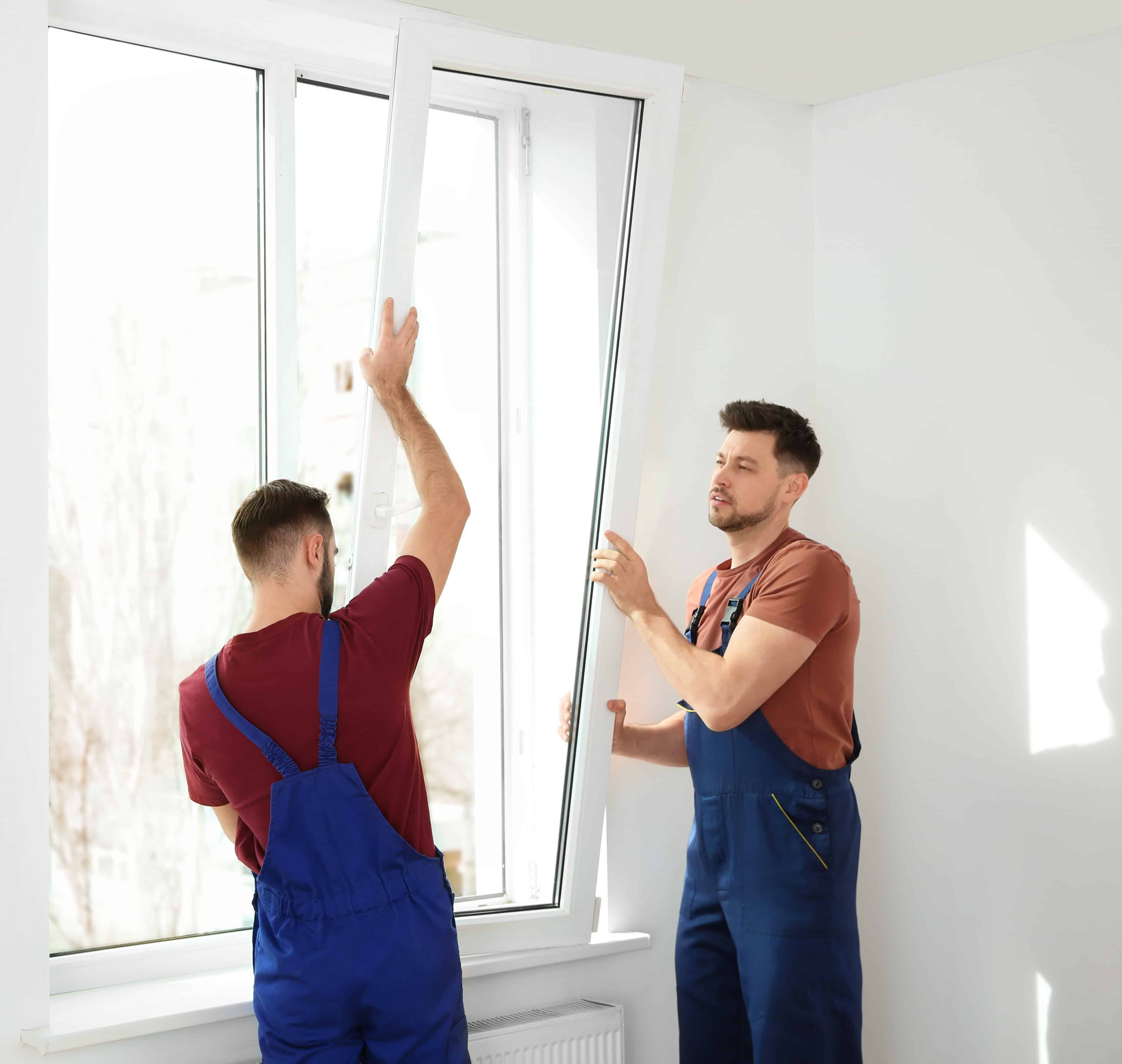 Construction workers repairing plastic window in house