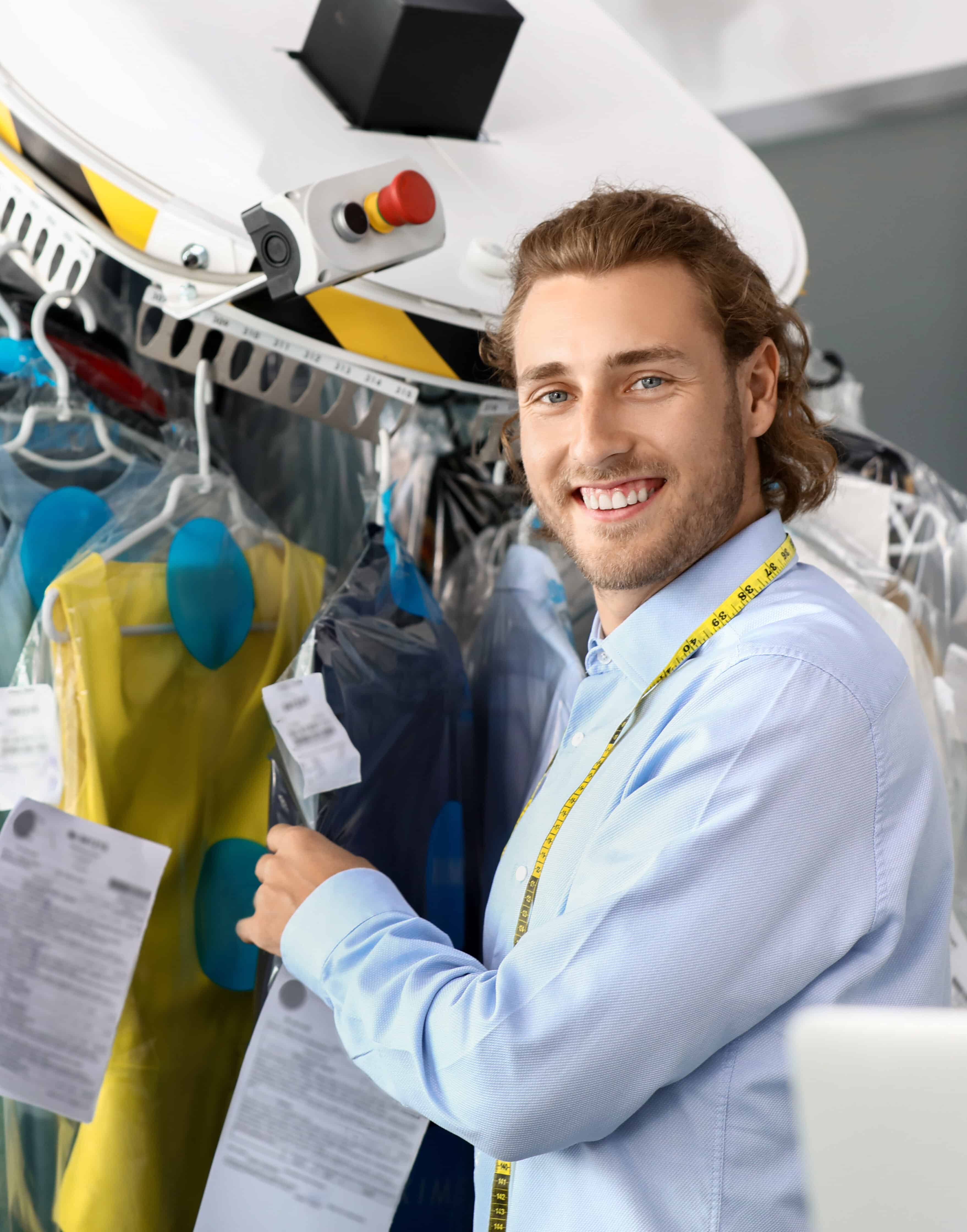 Worker of modern dry-cleaner's near rack with clothes