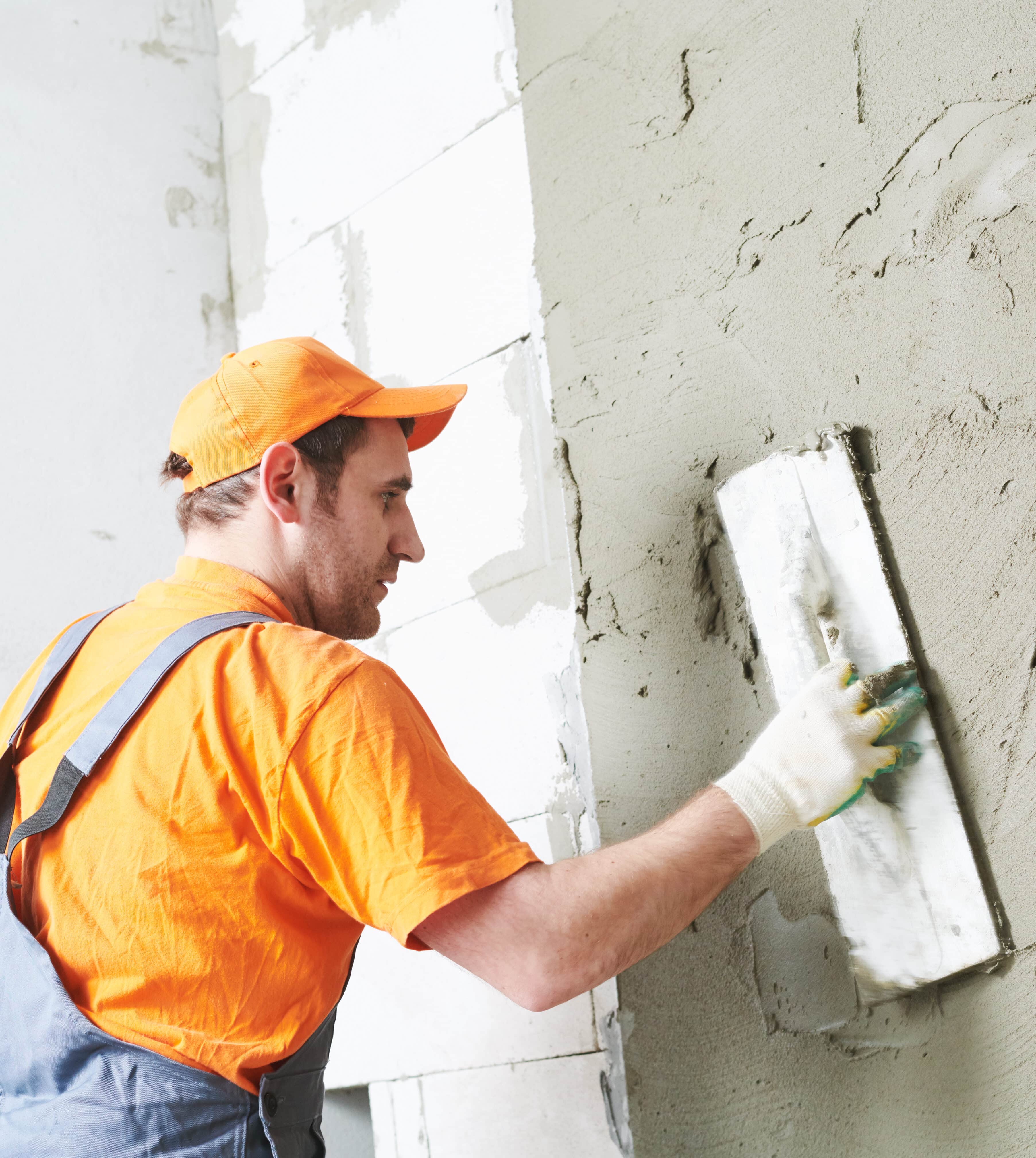 Rendererr spreading or applying putty plaster layer before finishing coating on brick wall from aerated concrete blocks