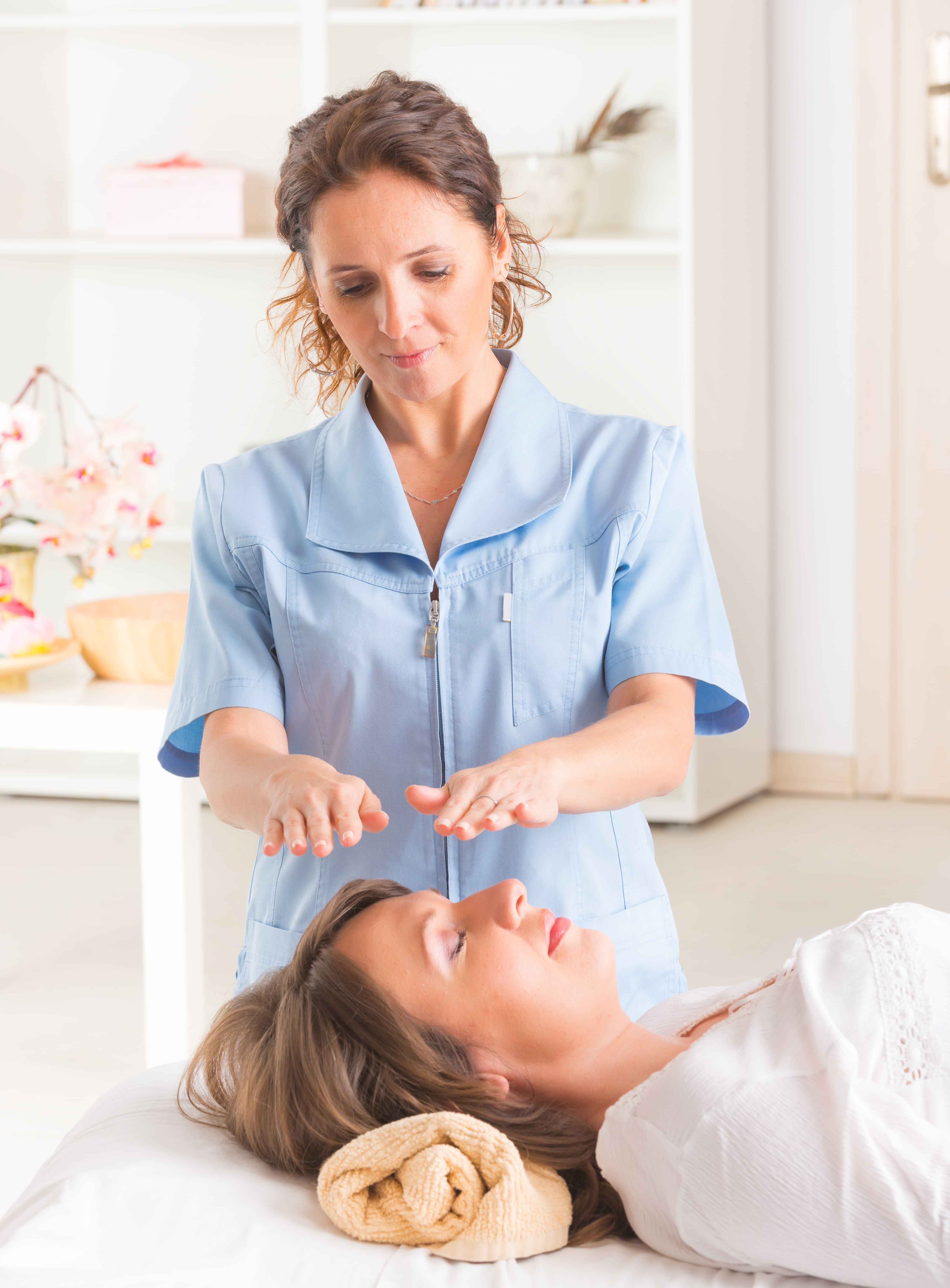 Professional Reiki healer doing reiki treatment to young woman